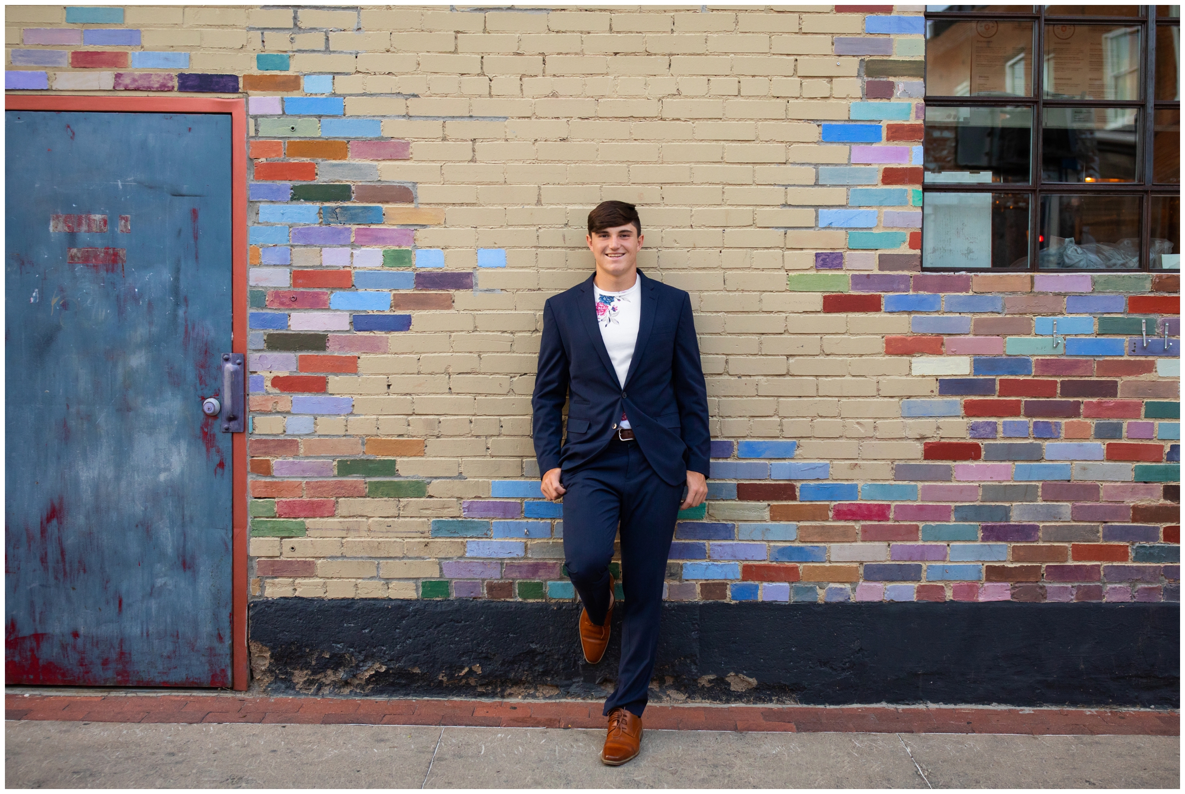 senior guy leaning against painted brick wall in Boulder Colorado alley