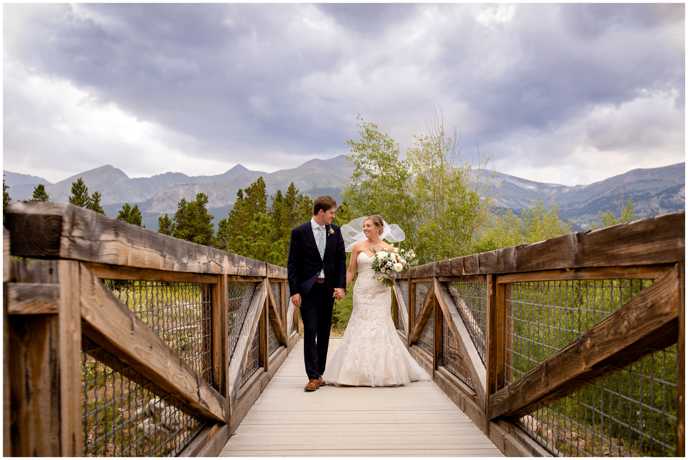 couple walking across wooden bridge in Breckenridge Colorado during mountain lodge wedding pictures 