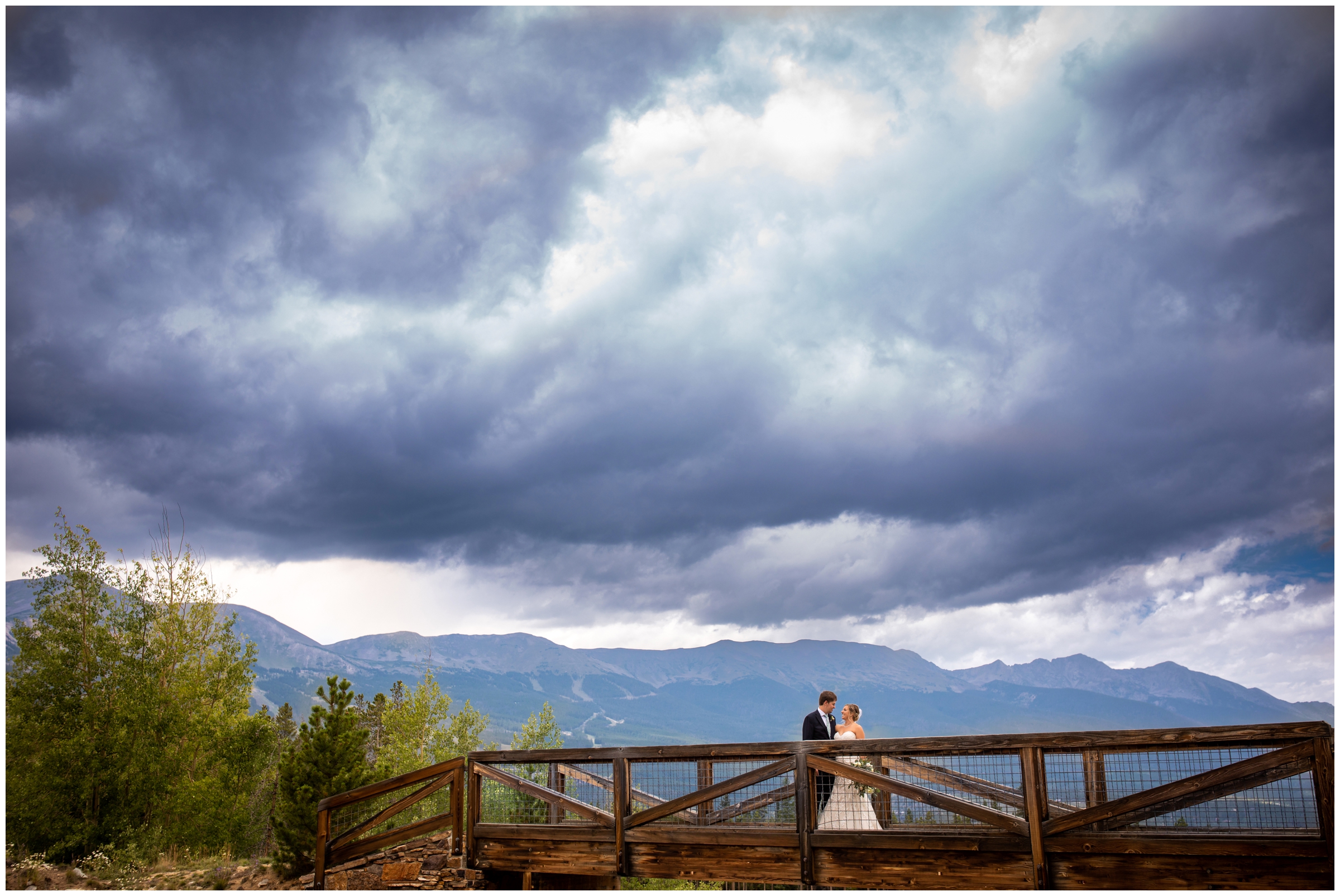 couple posing on wooden bridge with dramatic skies during Lodge at Breckenridge Colorado wedding photos