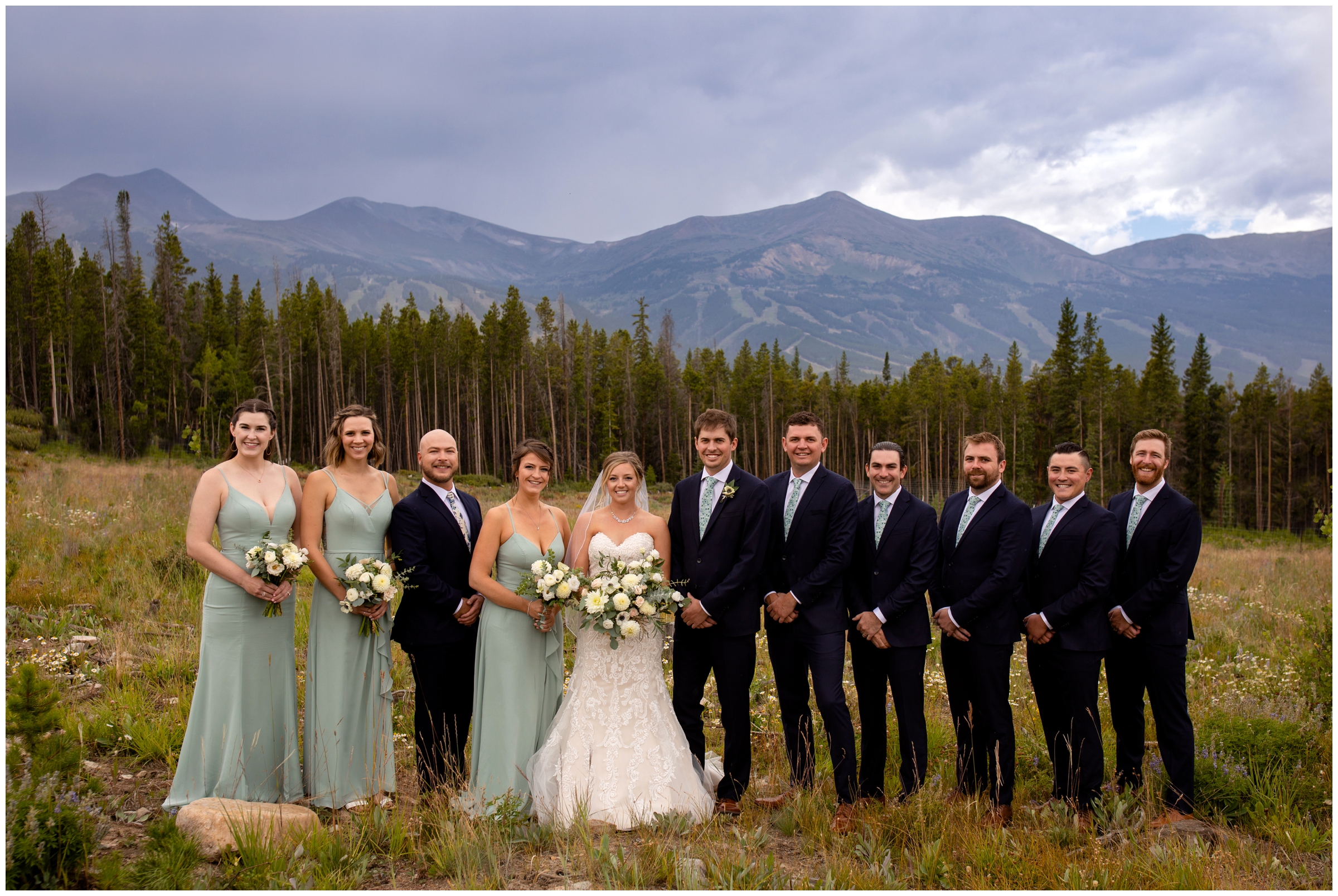 wedding party in sage green and black posing in front of mountains on Boreas Pass during Breckenridge Colorado wedding photos 