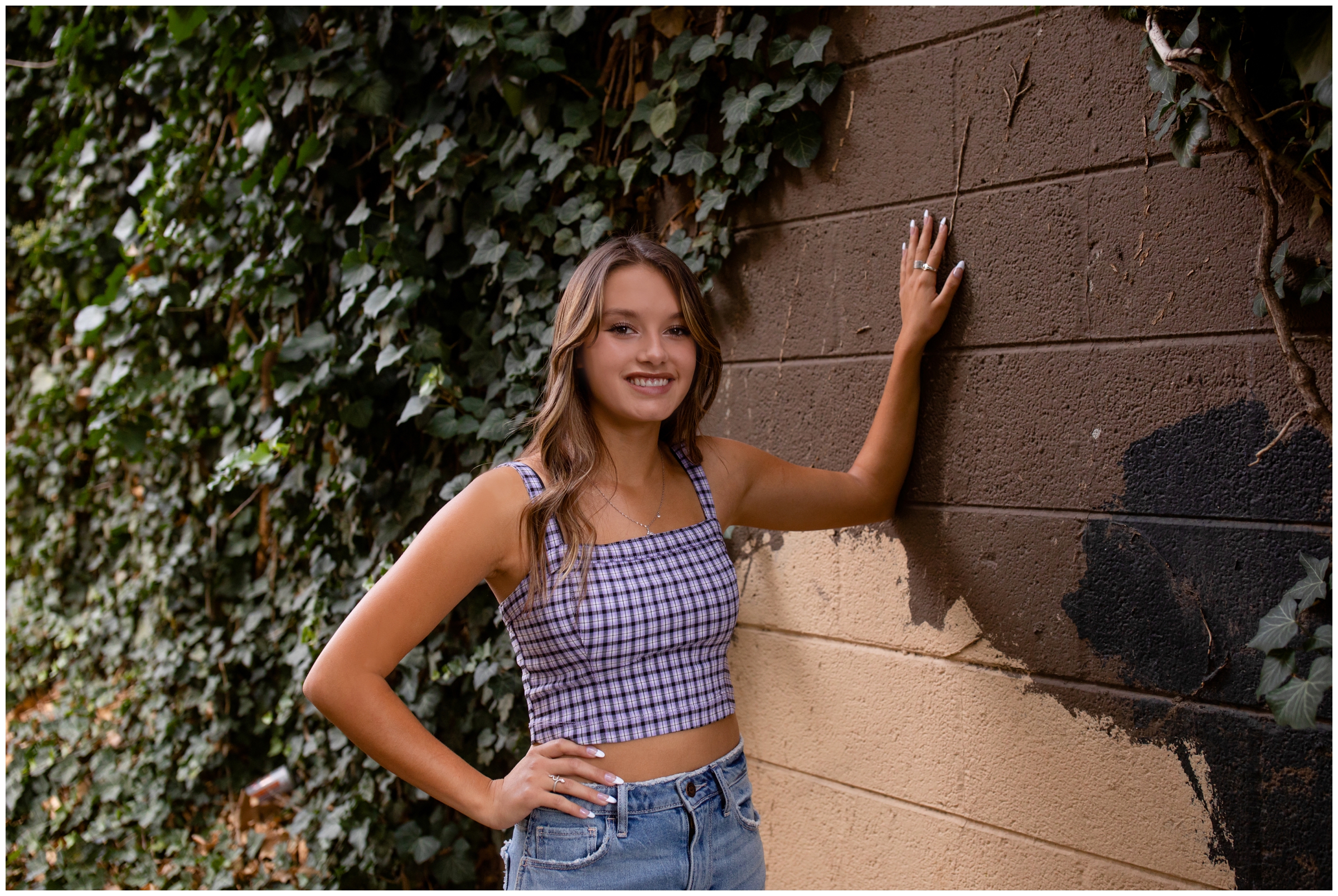 teen girl leaning against ivy wall during Colorado urban senior photos