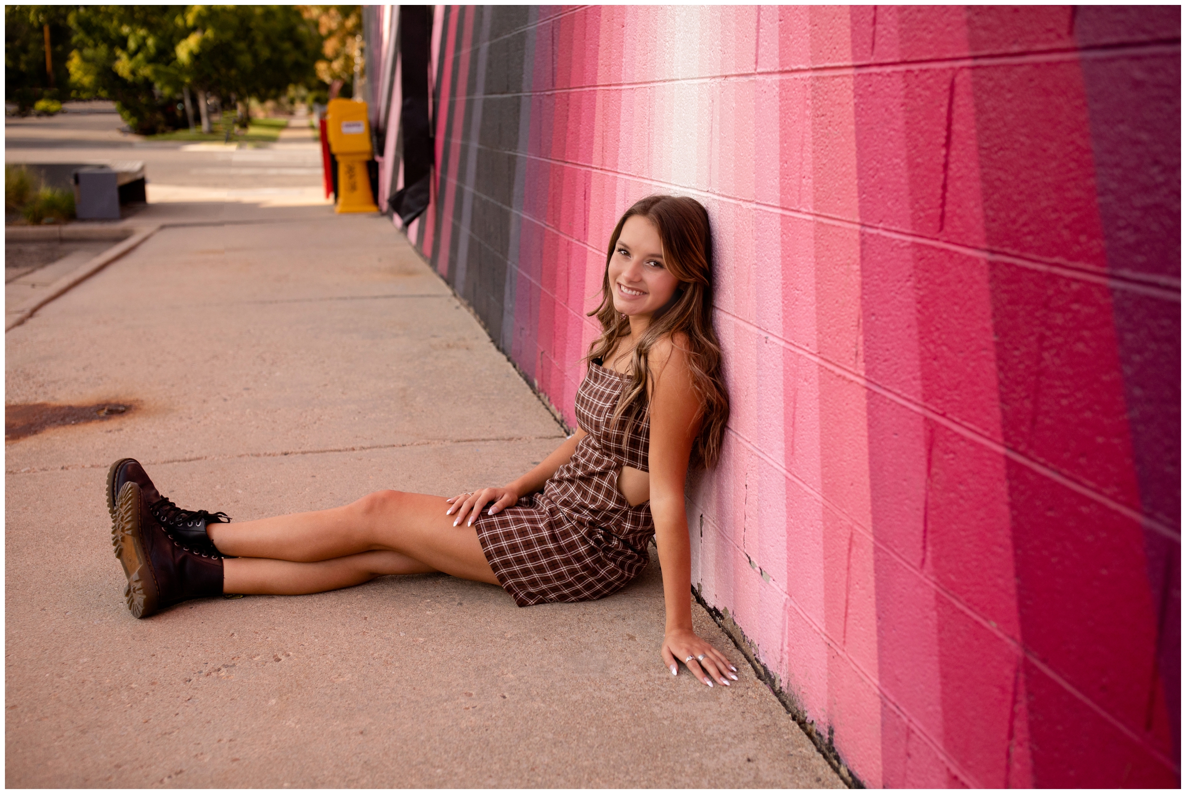 teen girl leaning against colorful wall mural during urban Boulder senior portraits 
