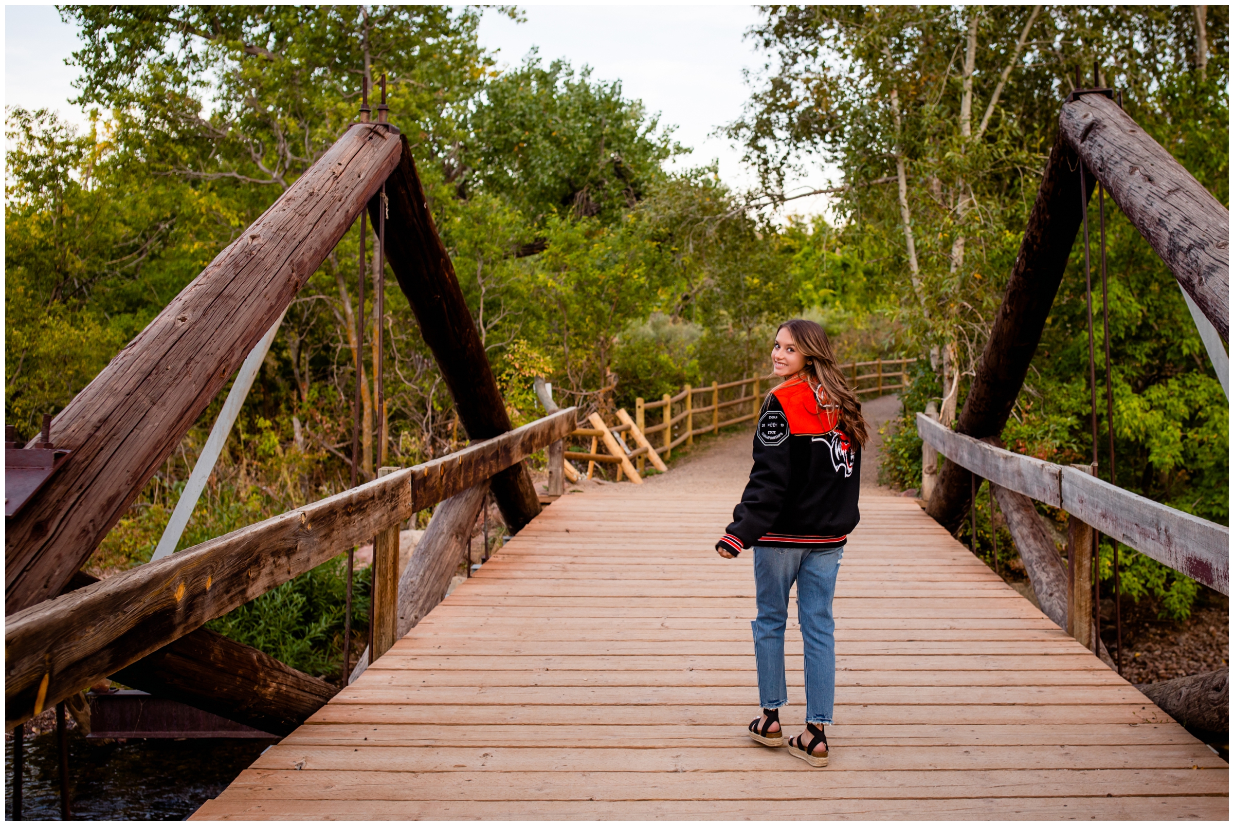 teen walking on wooden bridge during Colorado nature senior pictures at South Mesa Trail Boulder