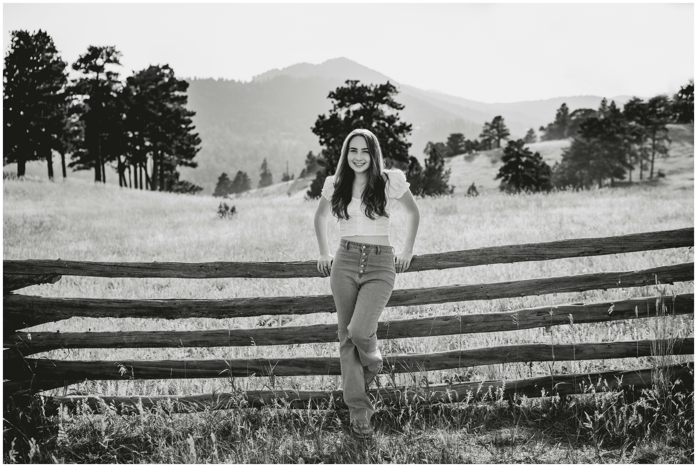 teen leaning against rustic wooden fence during Boulder CO senior photos at Betasso Preserve 