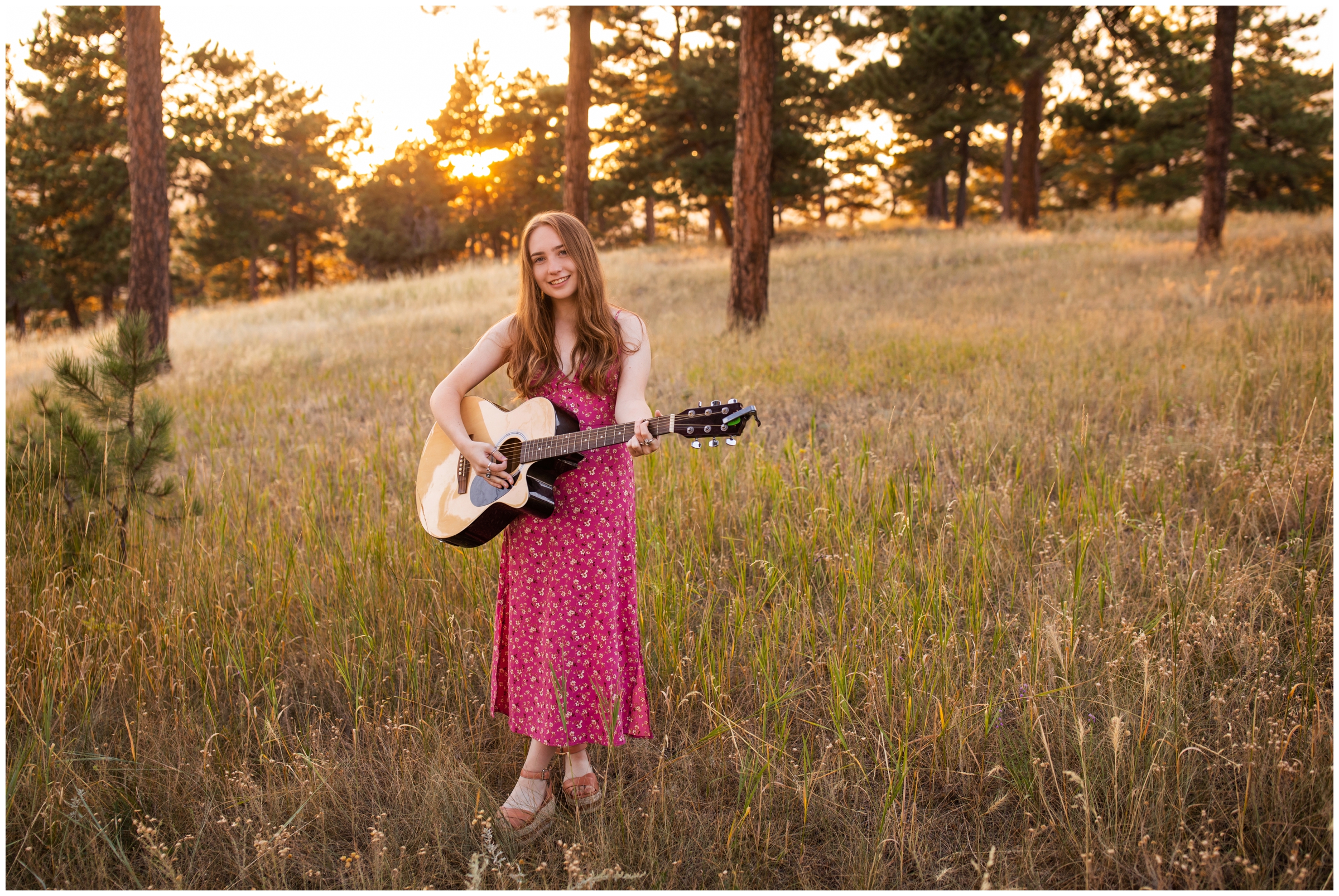 teen standing in field with guitar during unique senior pictures in Boulder Colorado