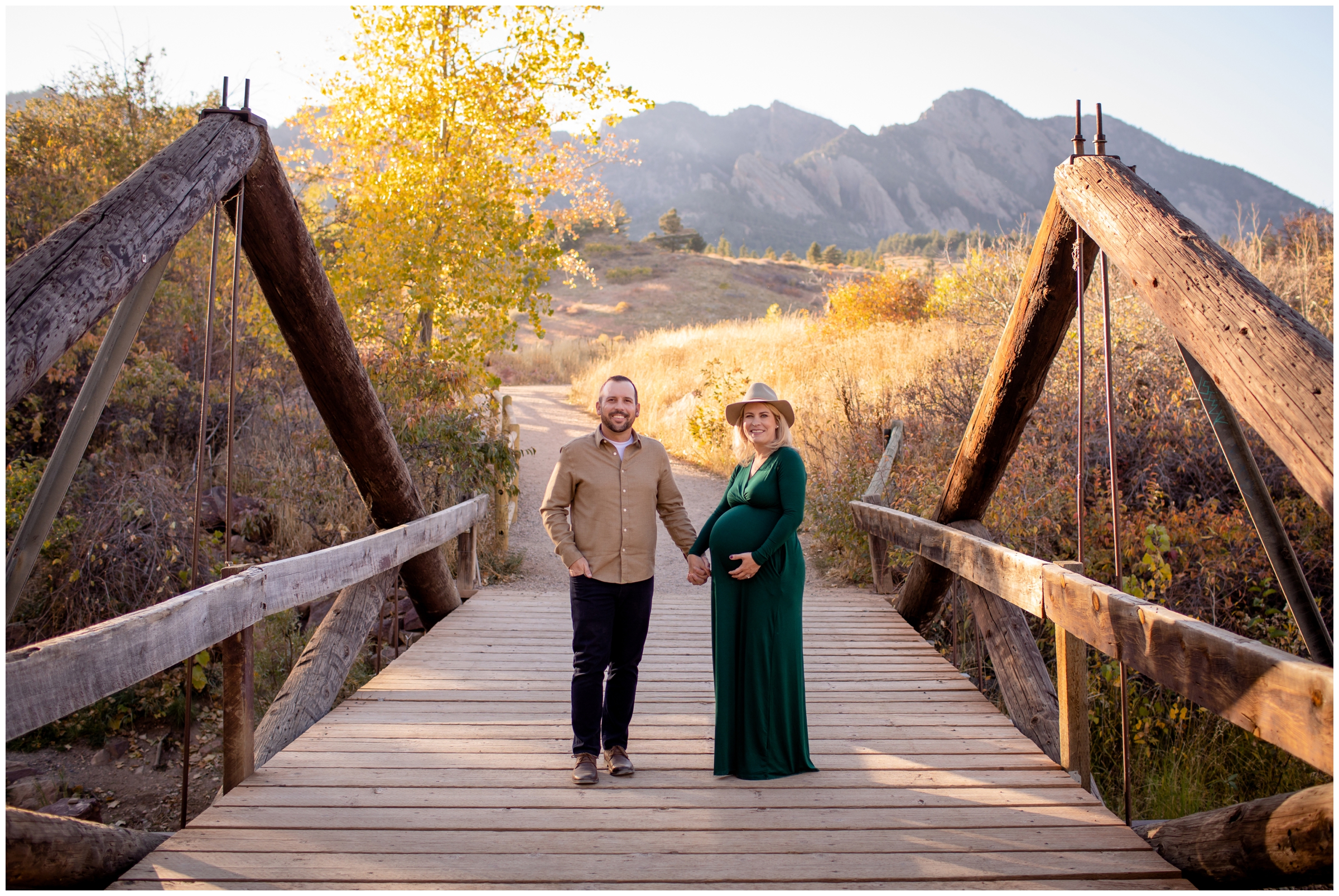 couple holding hands on a bridge during flatirons Boulder maternity portraits at South Mesa Trail