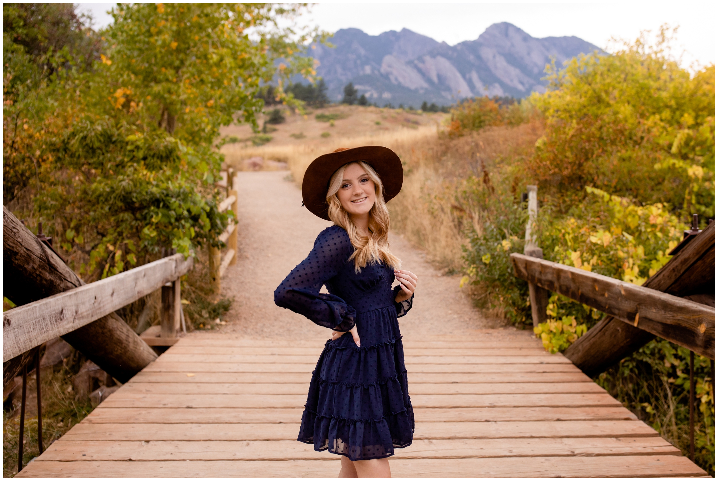 high school girl posing on wooden bridge with mountains in background during senior portraits in Boulder at South Mesa Trail by Colorado photographer Plum Pretty Photography