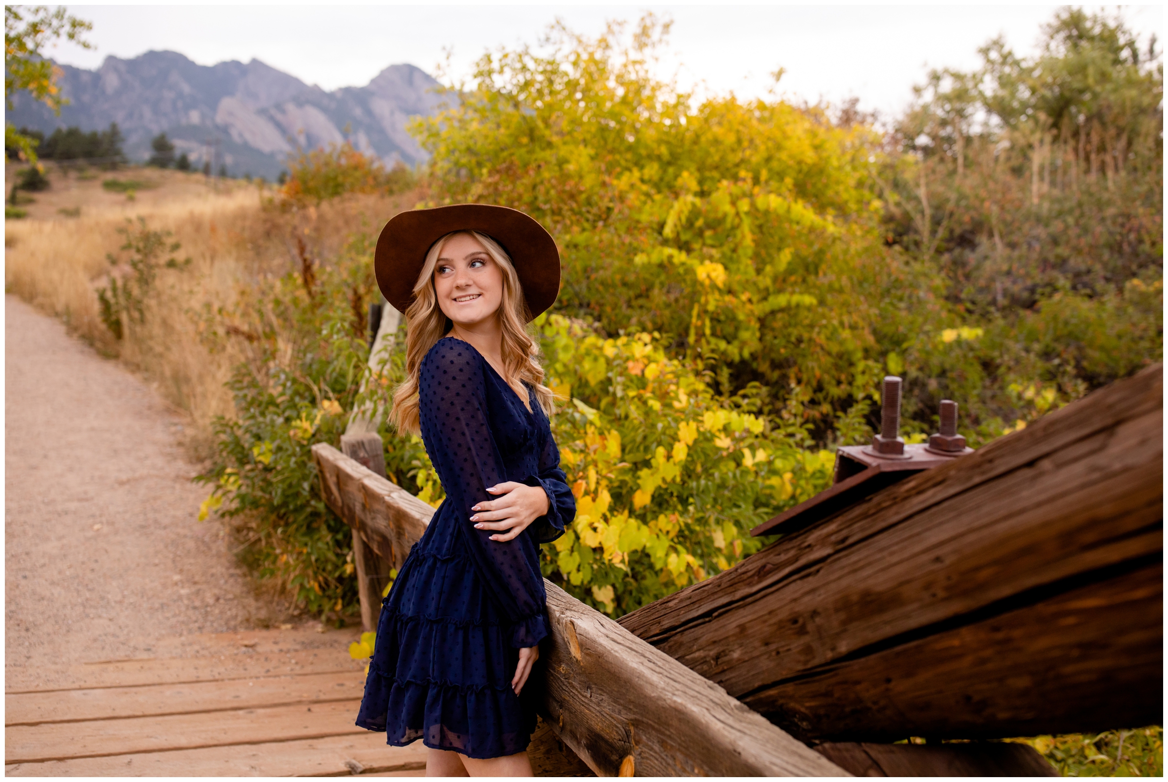 teen posing on wooden bridge with fall foliage in background during Boulder Colorado senior pictures 