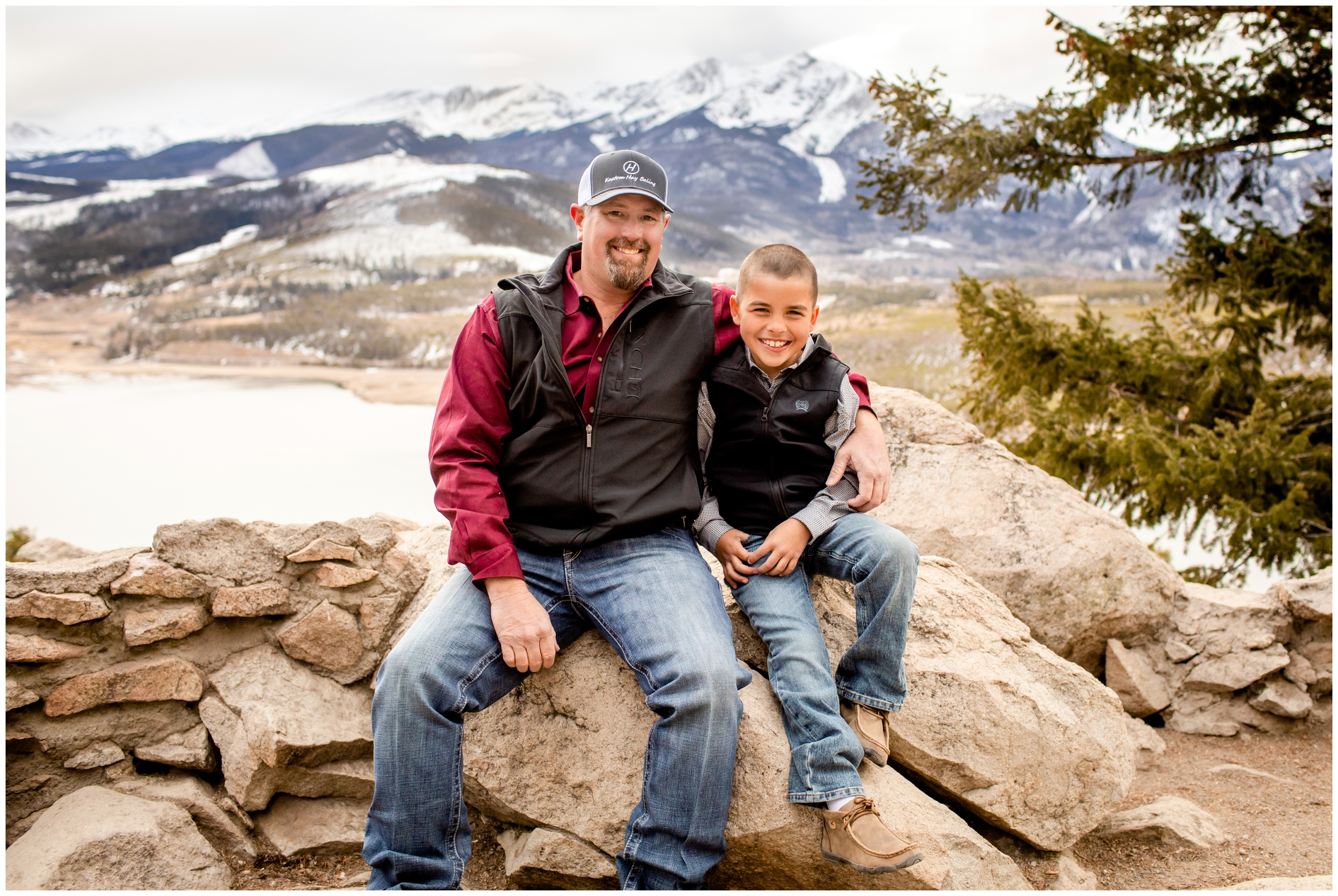 dad and son sitting on rock formations at Sapphire Point Overlook during Breckenridge Colorado family photos 