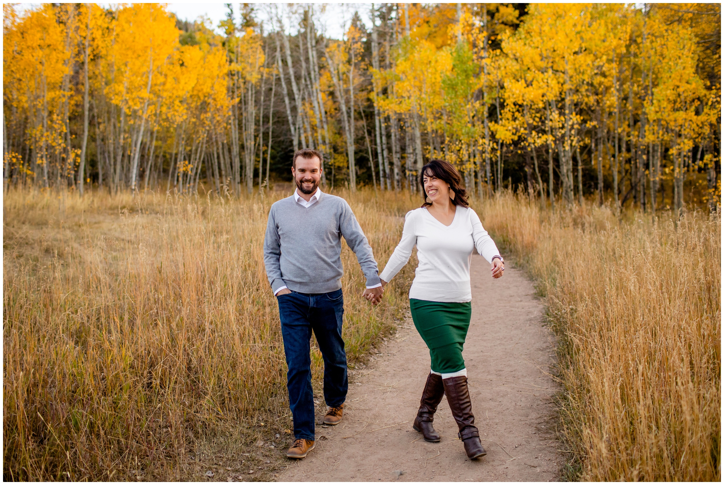 couple walking with aspen grove in background during candid Colorado fall mountain engagement photos