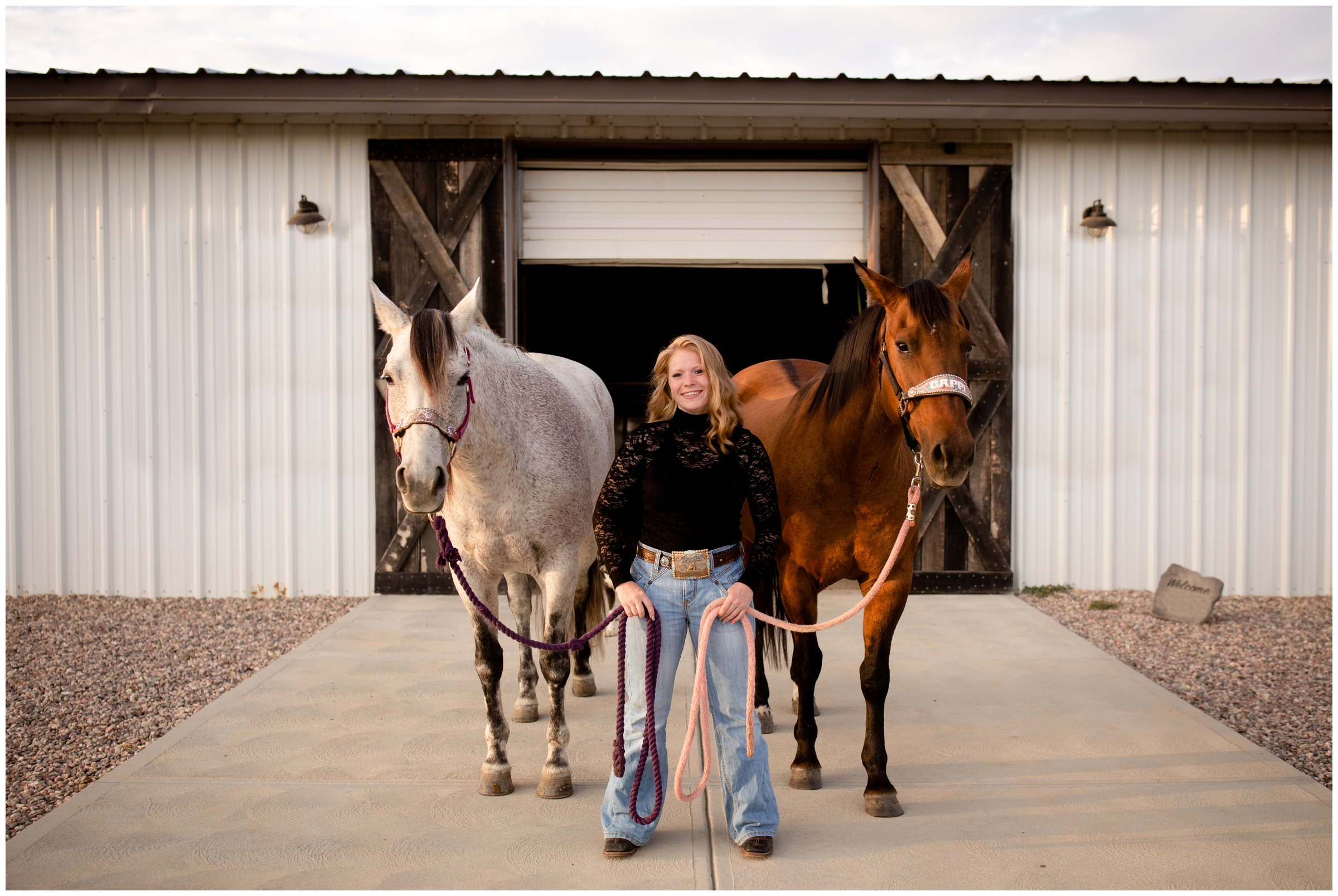 teen posing in front of horse stables with two horses during Loveland Colorado senior photos