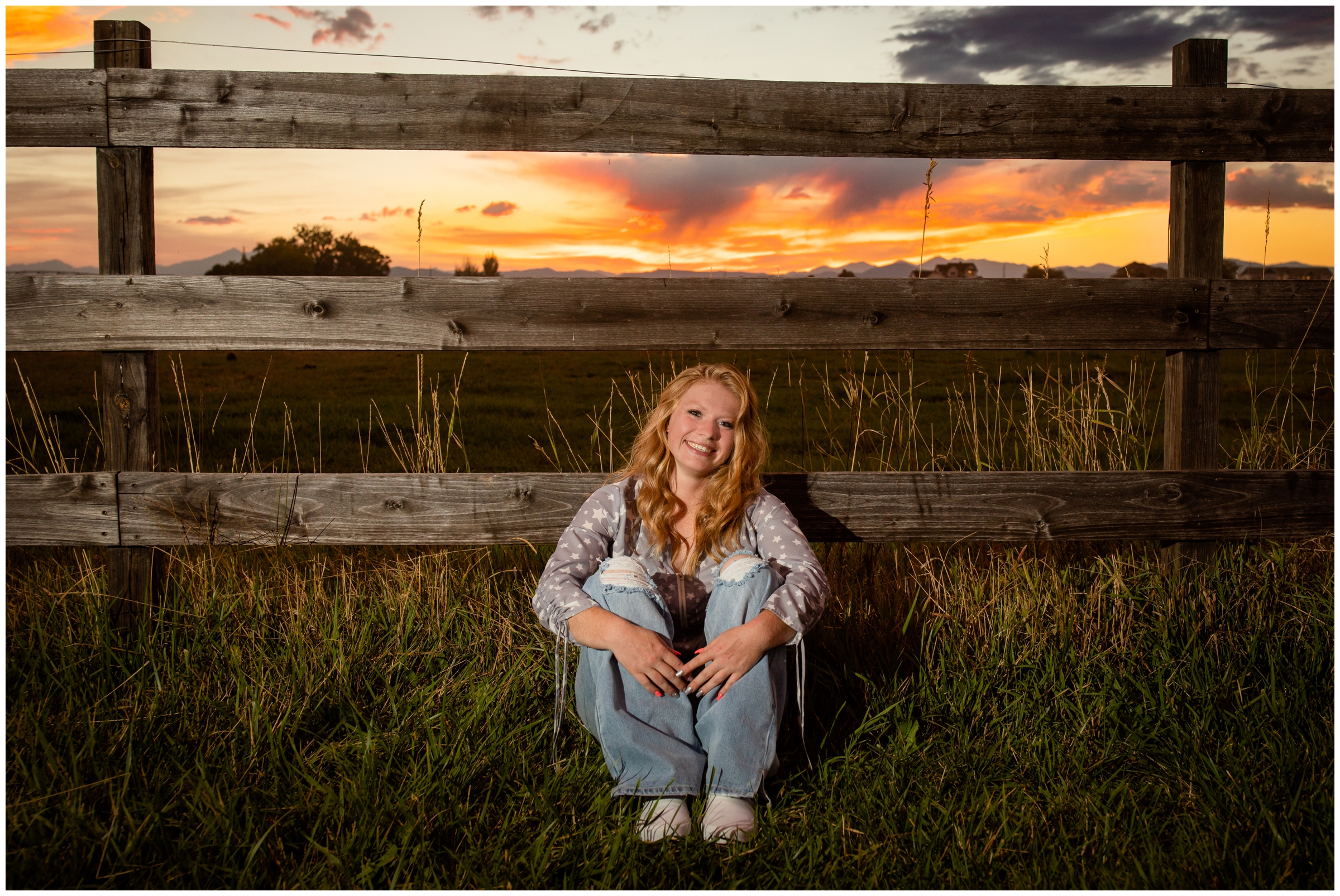 teen sitting against a fence during rustic farm senior pictures in Johnstown Colorado 