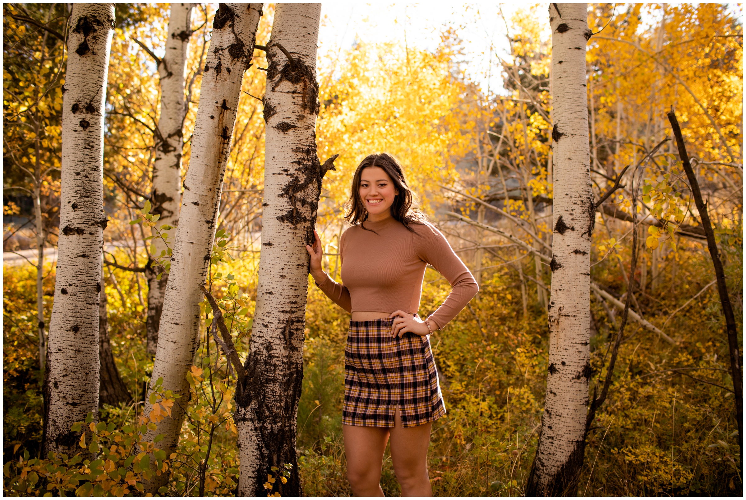 teen leaning against aspen tree during fall senior photography session in the Colorado mountains