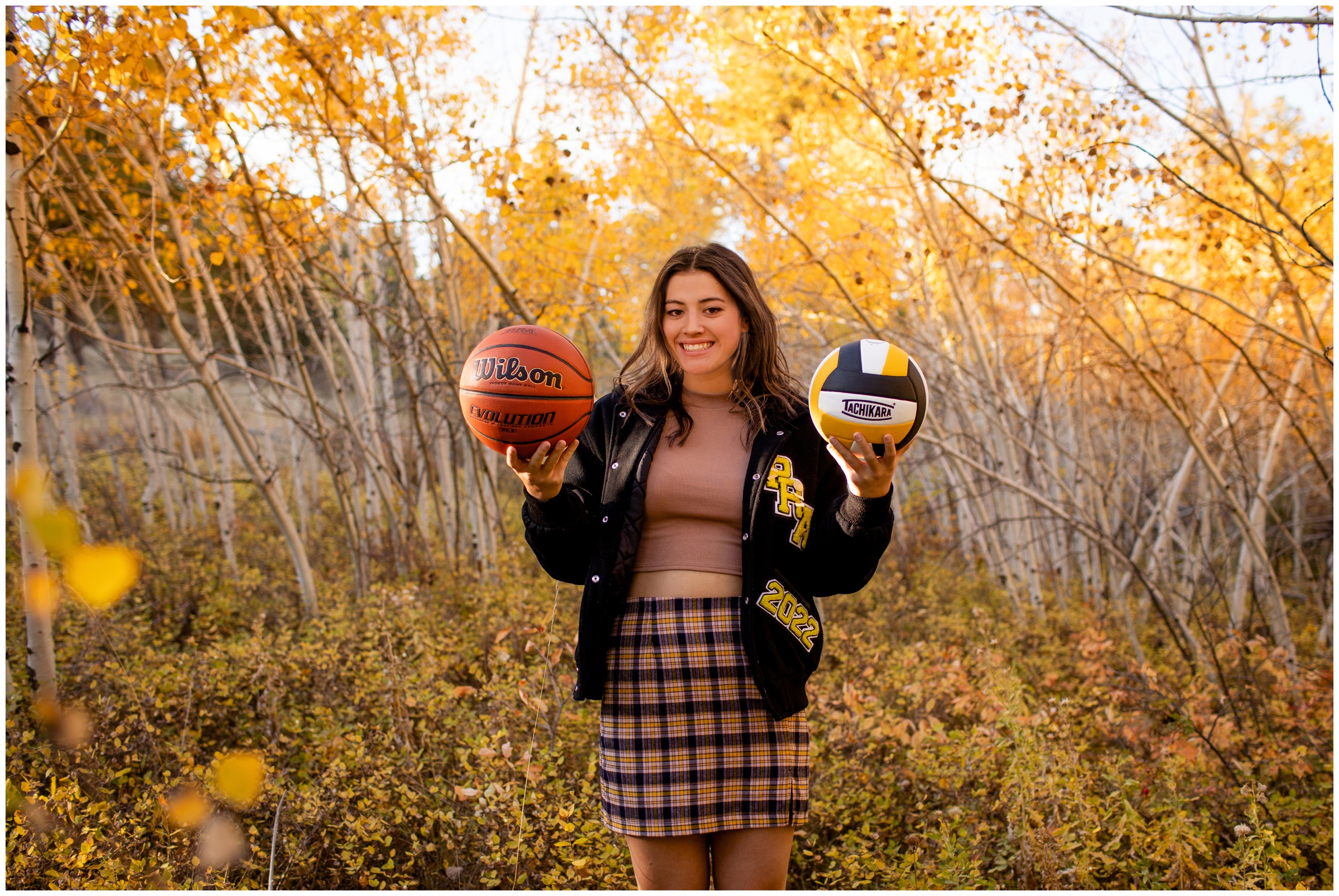 teen girl posing with a volleyball and basketball during Colorado sports senior pictures 
