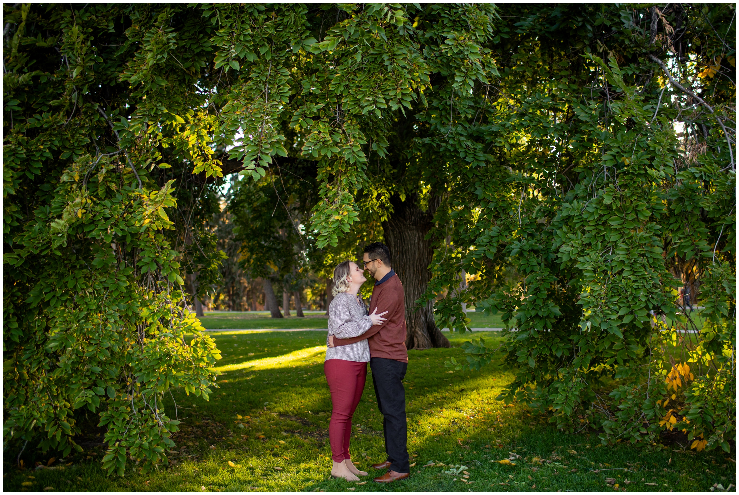 couple kissing under tree arch in park in Denver Colorado during Plum Pretty Photography photo shoot 