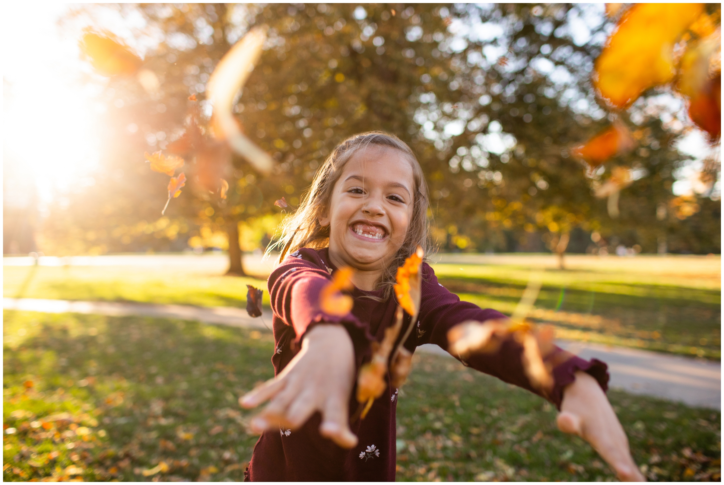 little girl throwing leaves at camera during Colorado family pictures at Cheesman Park Denver 