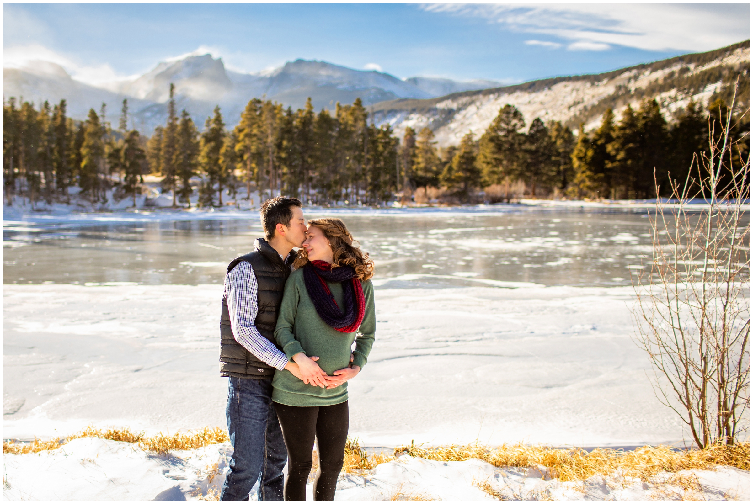 couple embracing with frozen lake in background during Estes Park Colorado winter maternity photos