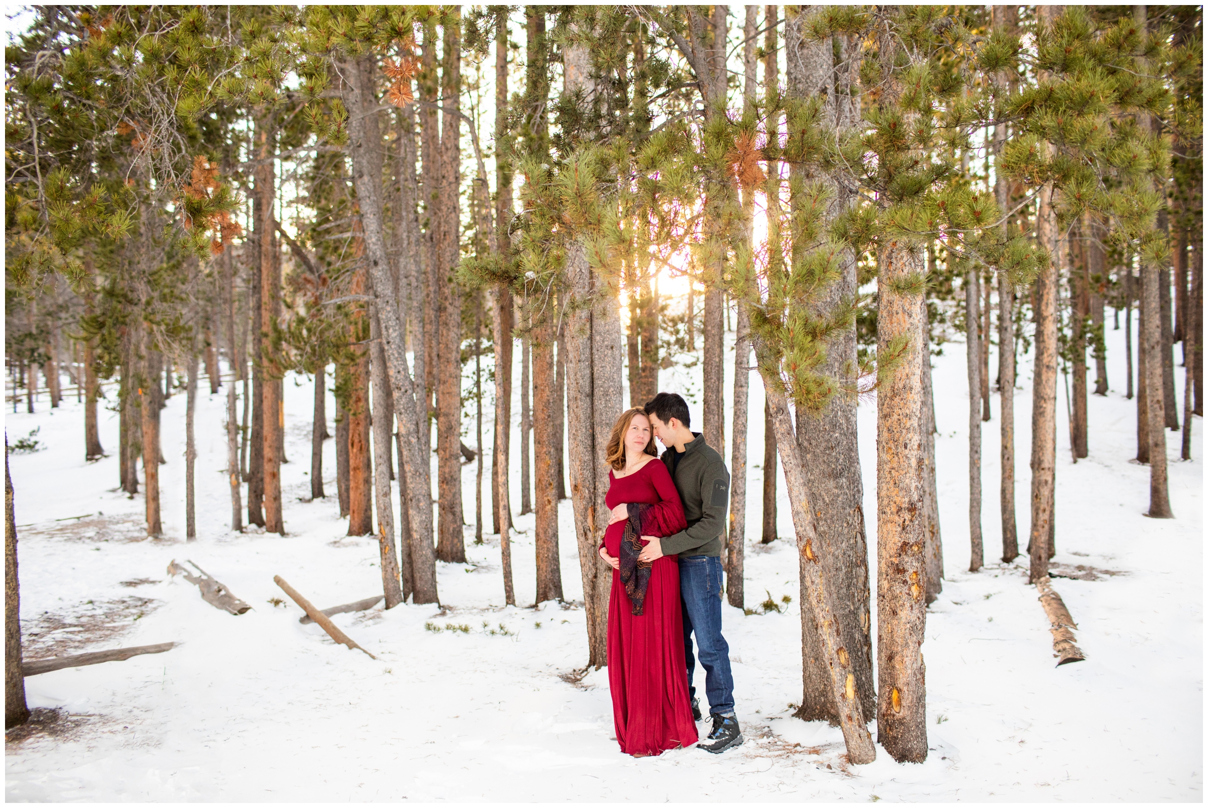 couple cuddling in snowy forest during Estes Park Colorado maternity pictures in RMNP