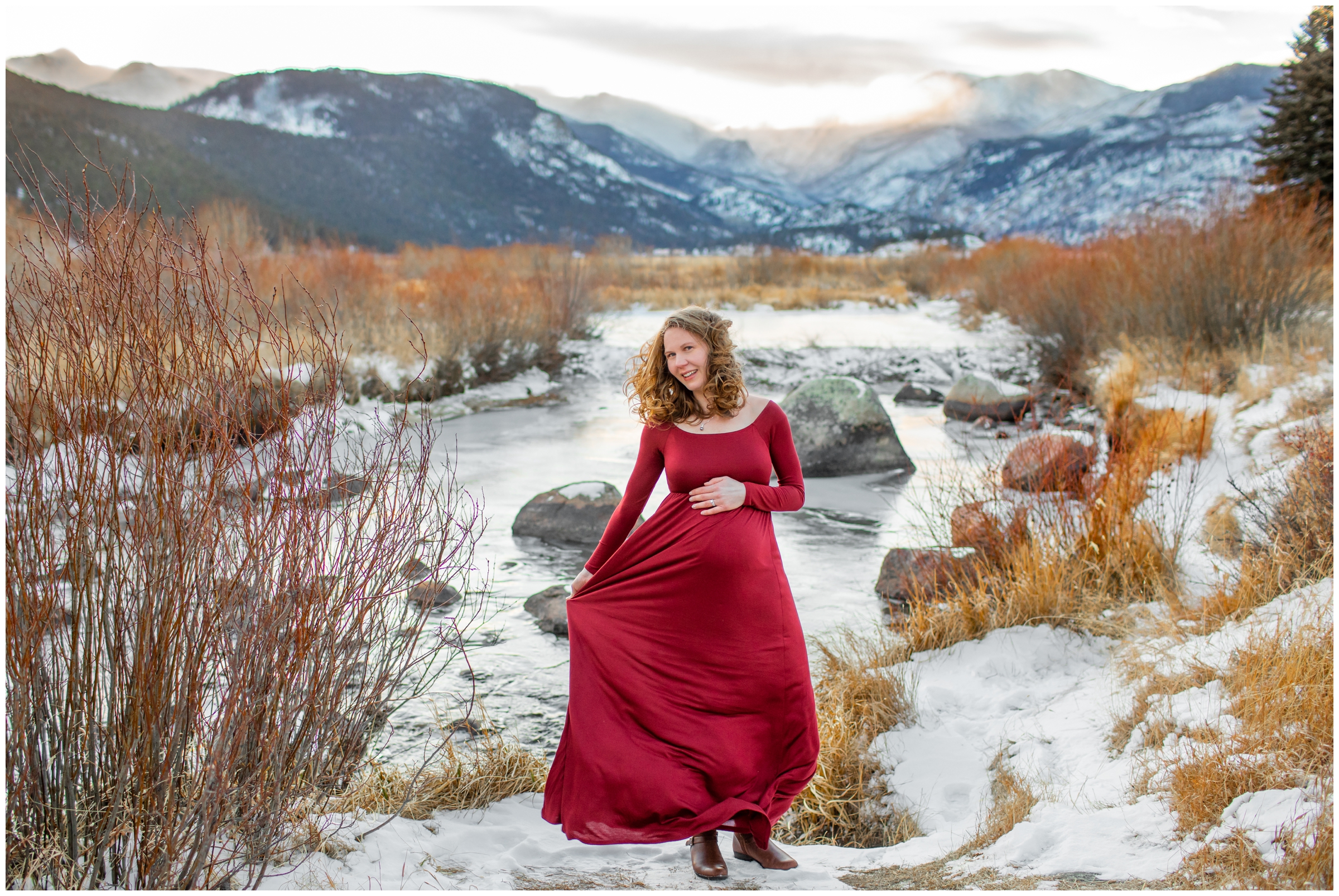 woman in red dress with snowy mountains in background during Estes Park Colorado winter maternity pictures 