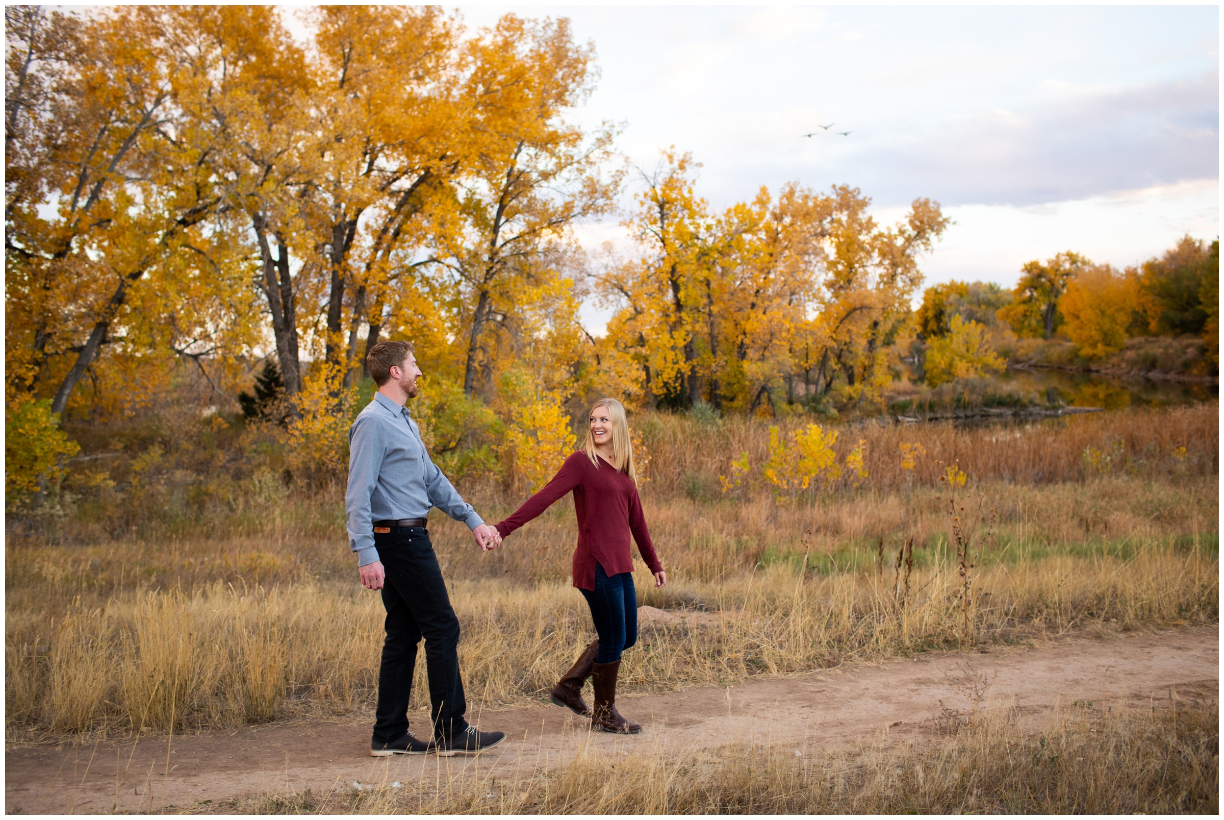 couple walking with fall foliage in background at Riverbend Ponds Colorado engagement portraits 