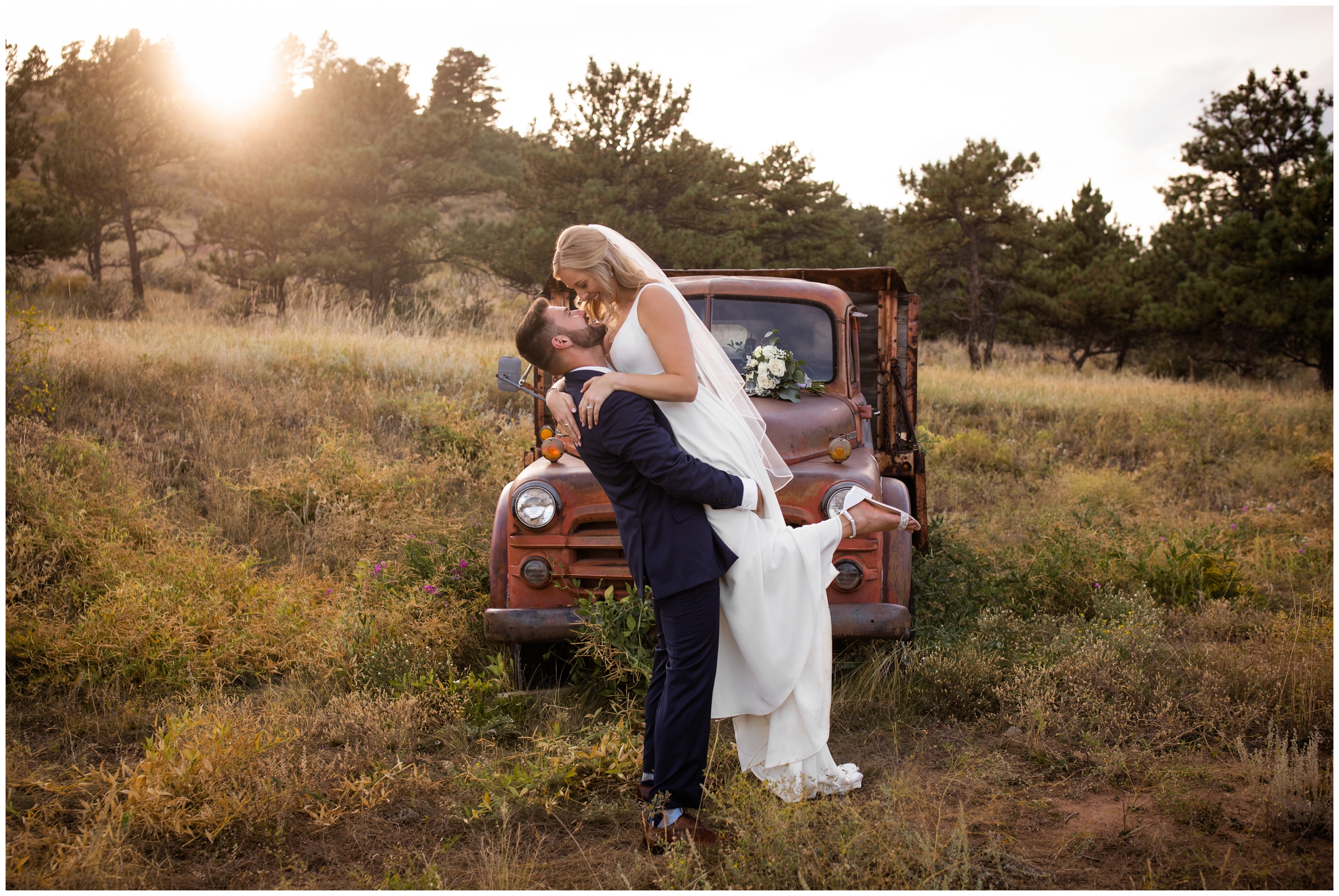 groom lifting bride with vintage truck in background during fall Colorado wedding at Lionscrest Manor