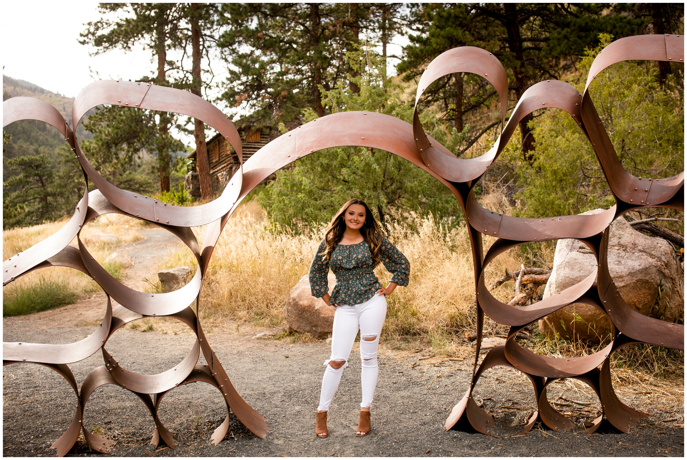 teen girl posing under metal art sculpture during Loveland Colorado senior photos by Plum Pretty Photography