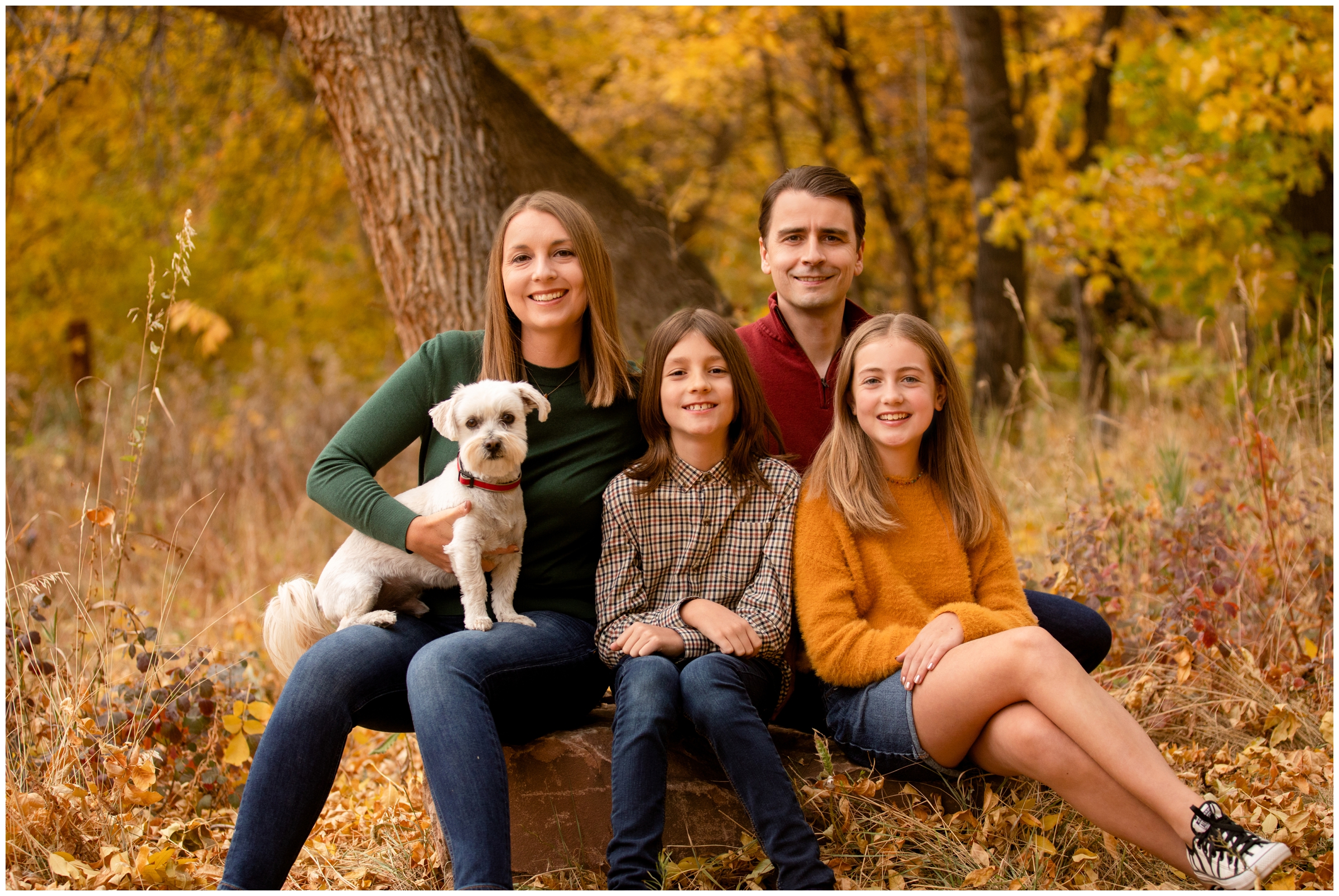 family sitting on large rock with fall foliage in background during Lavern Johnson Lyons family photography session 