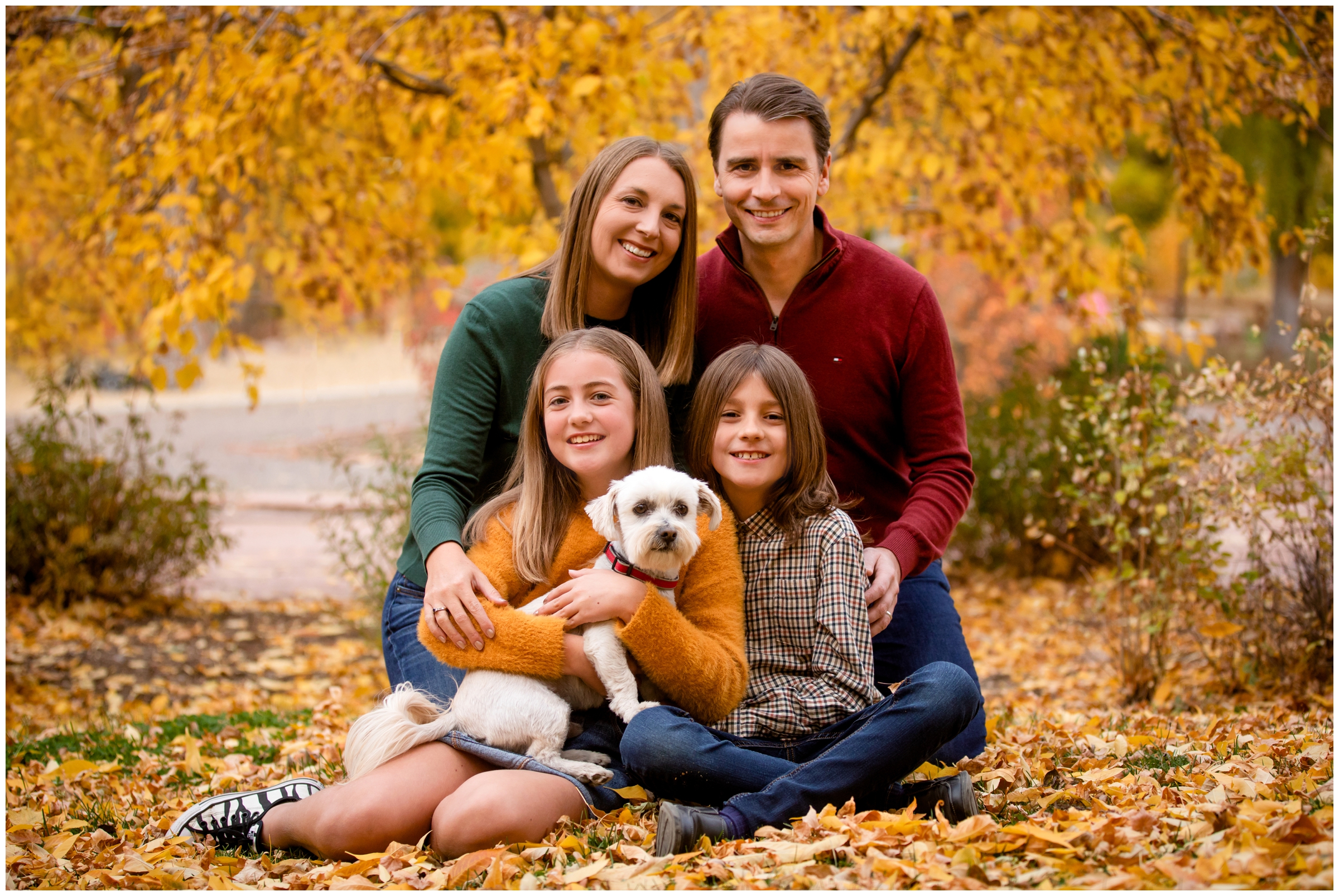 family sitting in a pile of leaves during fall family pictures in Lyons Colorado 