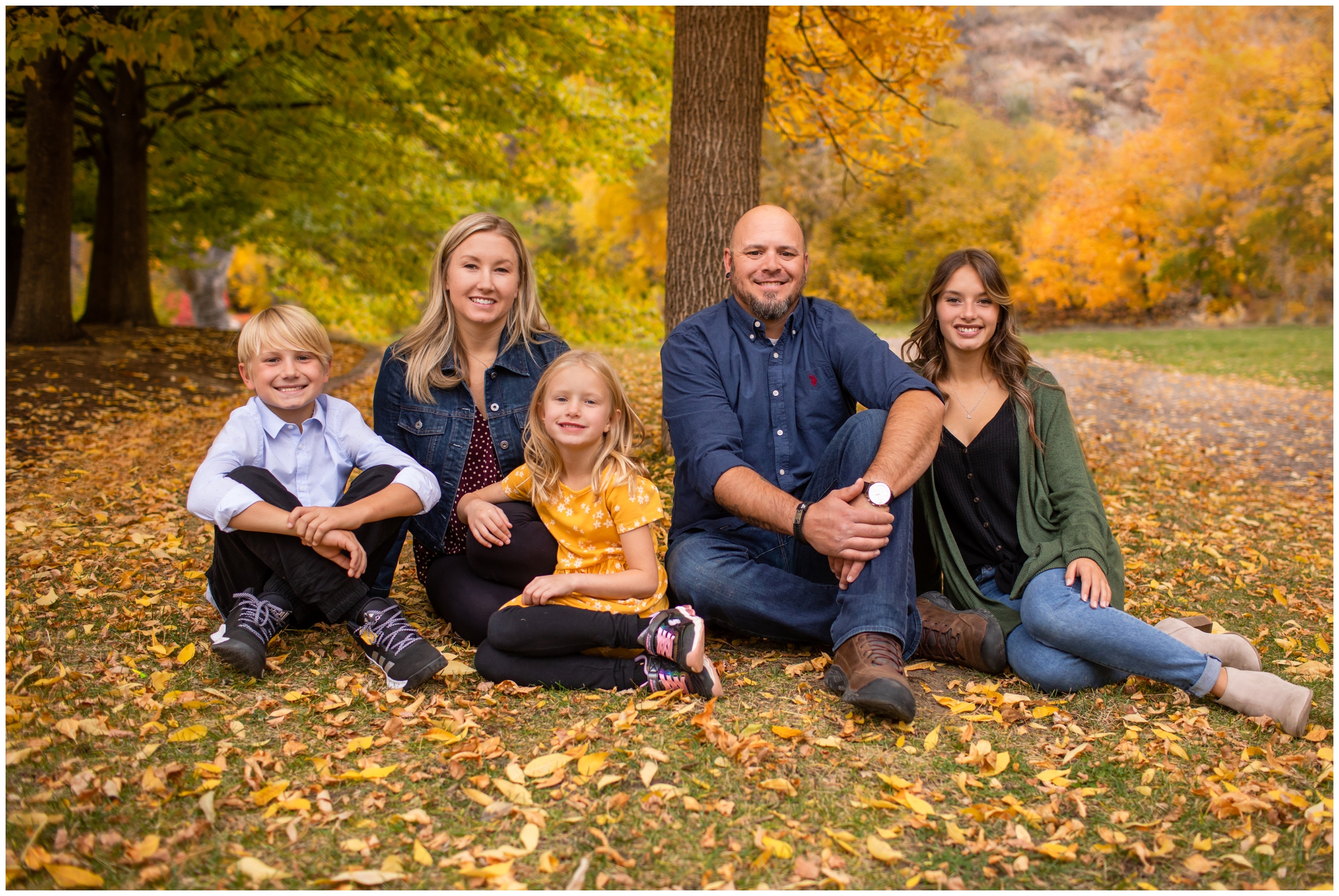 family sitting in leaves at Lyons family pictures during fall at Lavern M Johnson Park Colorado