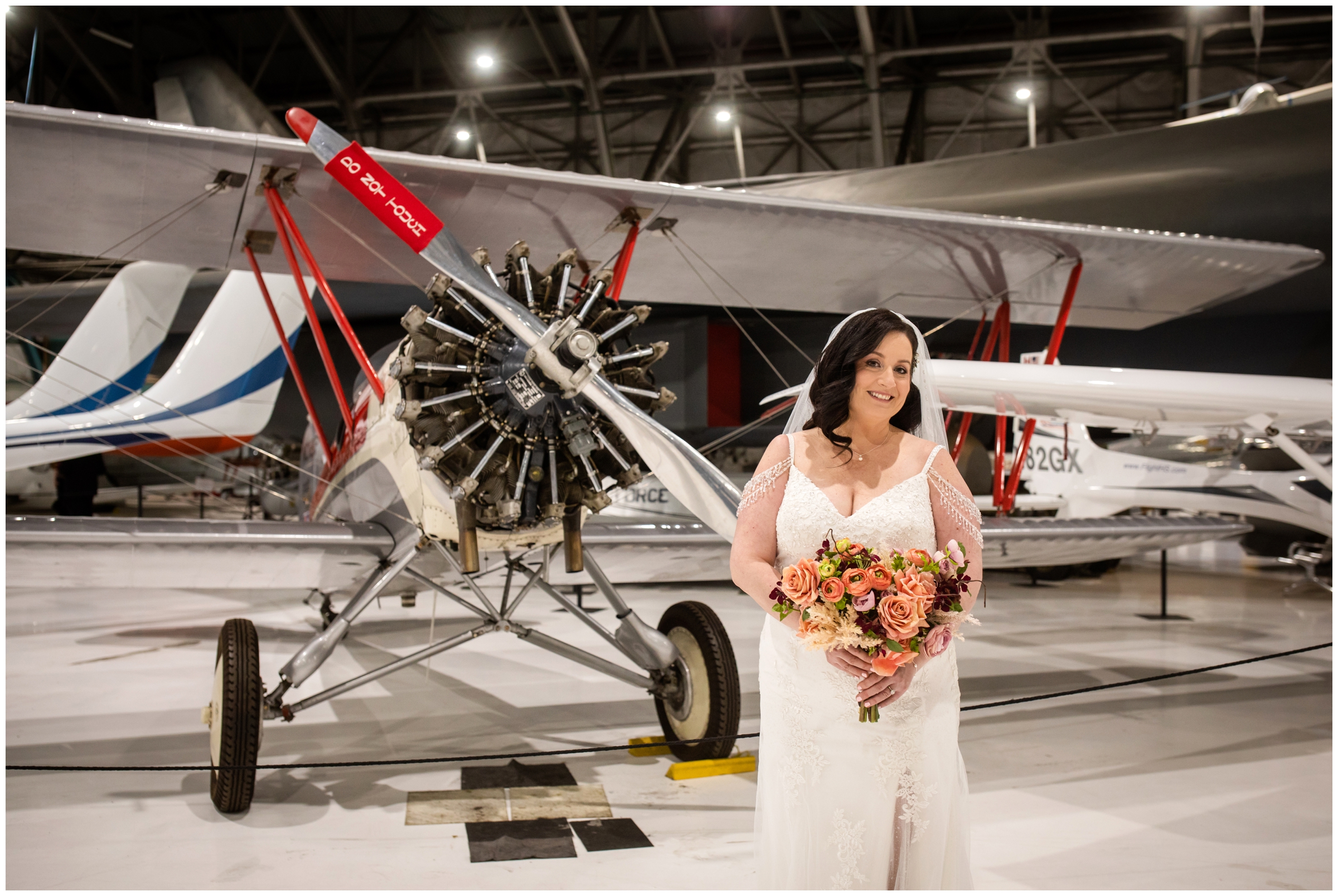 bride posing in front of an airplane during Wings over the Rockies museum wedding portraits 