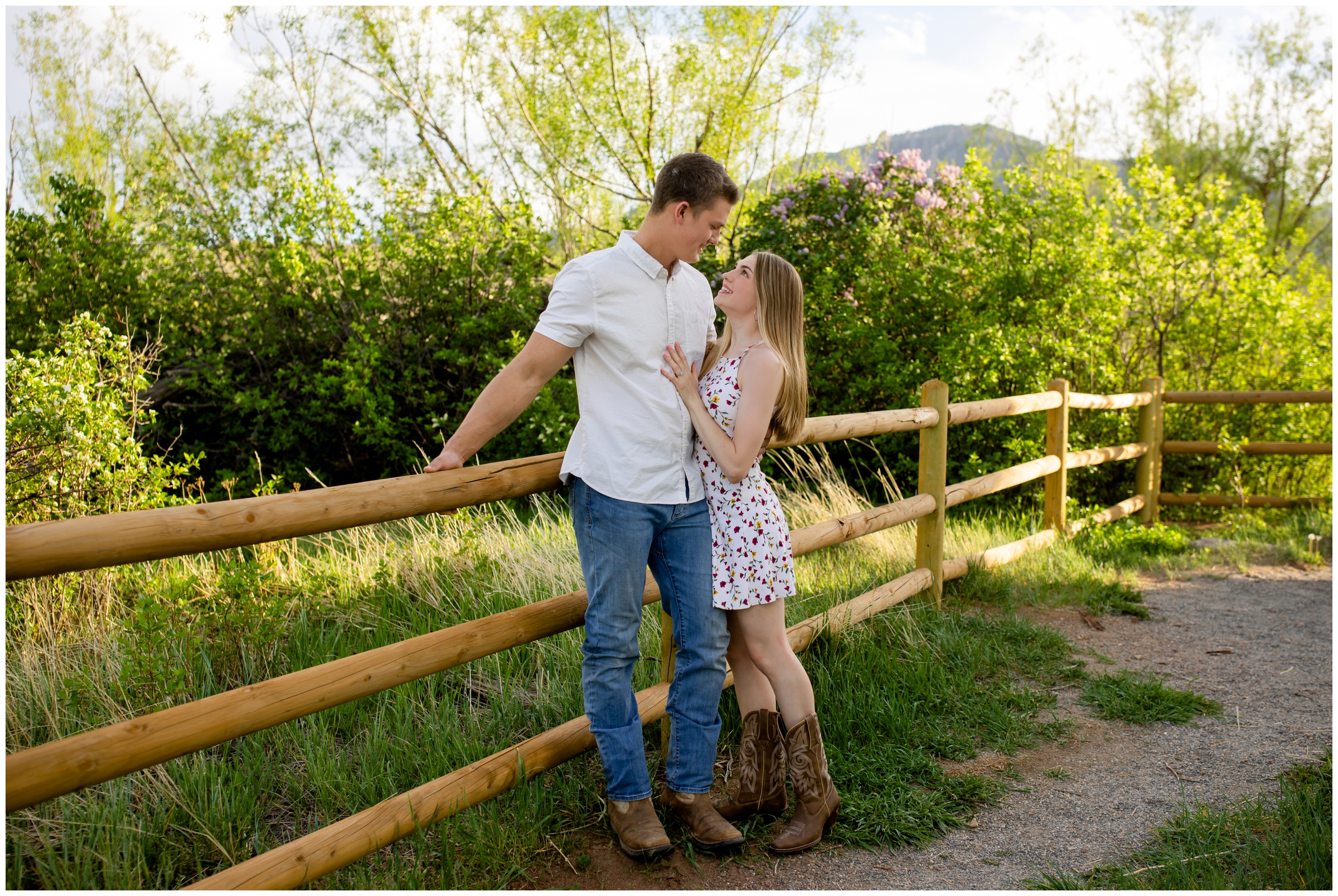 couple leaning against fence with spring flowers in background during Colorado engagement photography session by Plum Pretty Photos