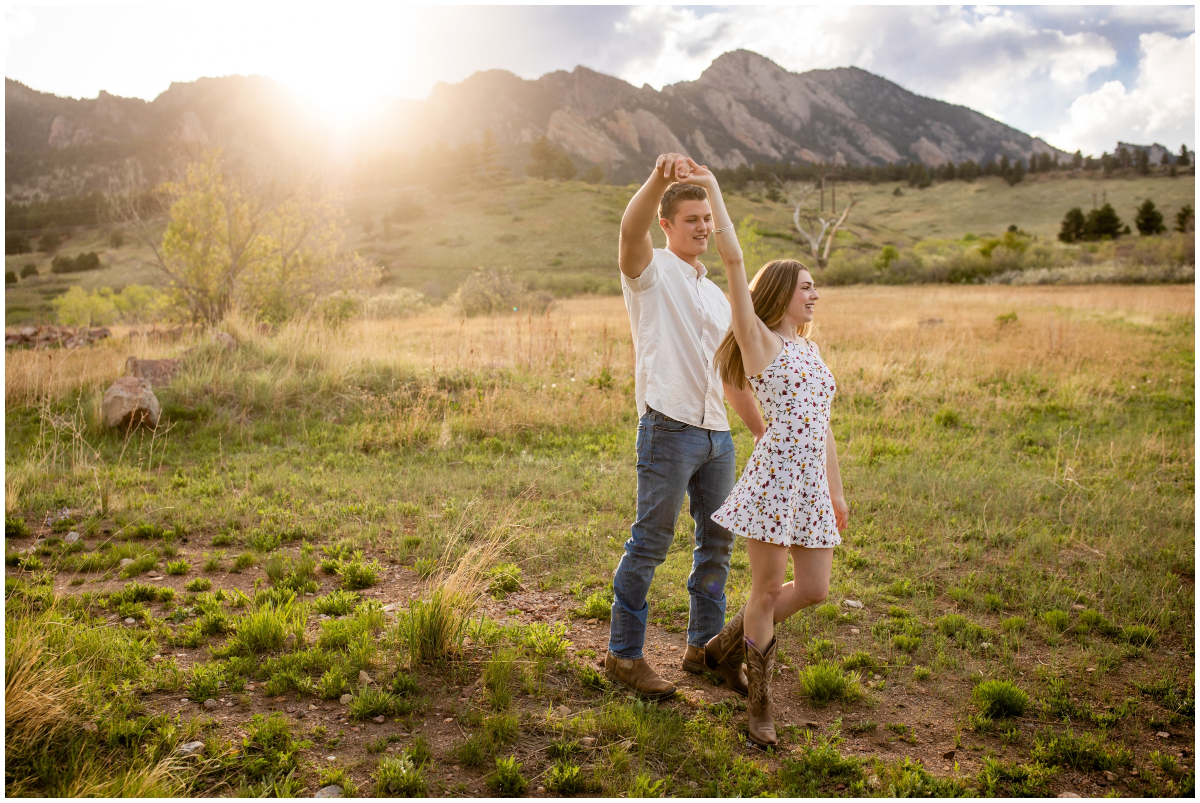 couple dancing in a field with mountains in background during Colorado engagement photography session at South Mesa trail