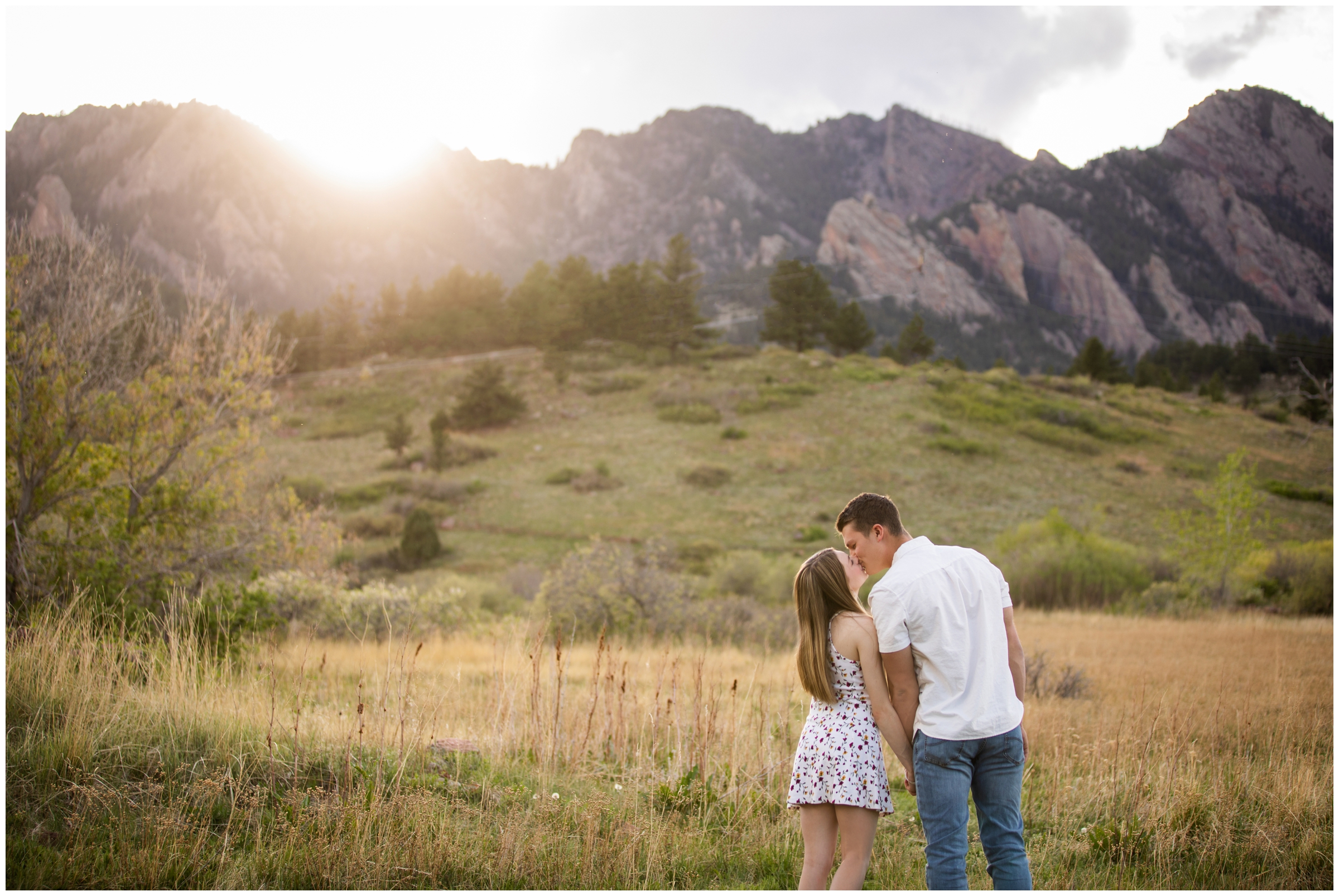 couple kissing with flatirons in background during Boulder Colorado engagement photography session during springtime 