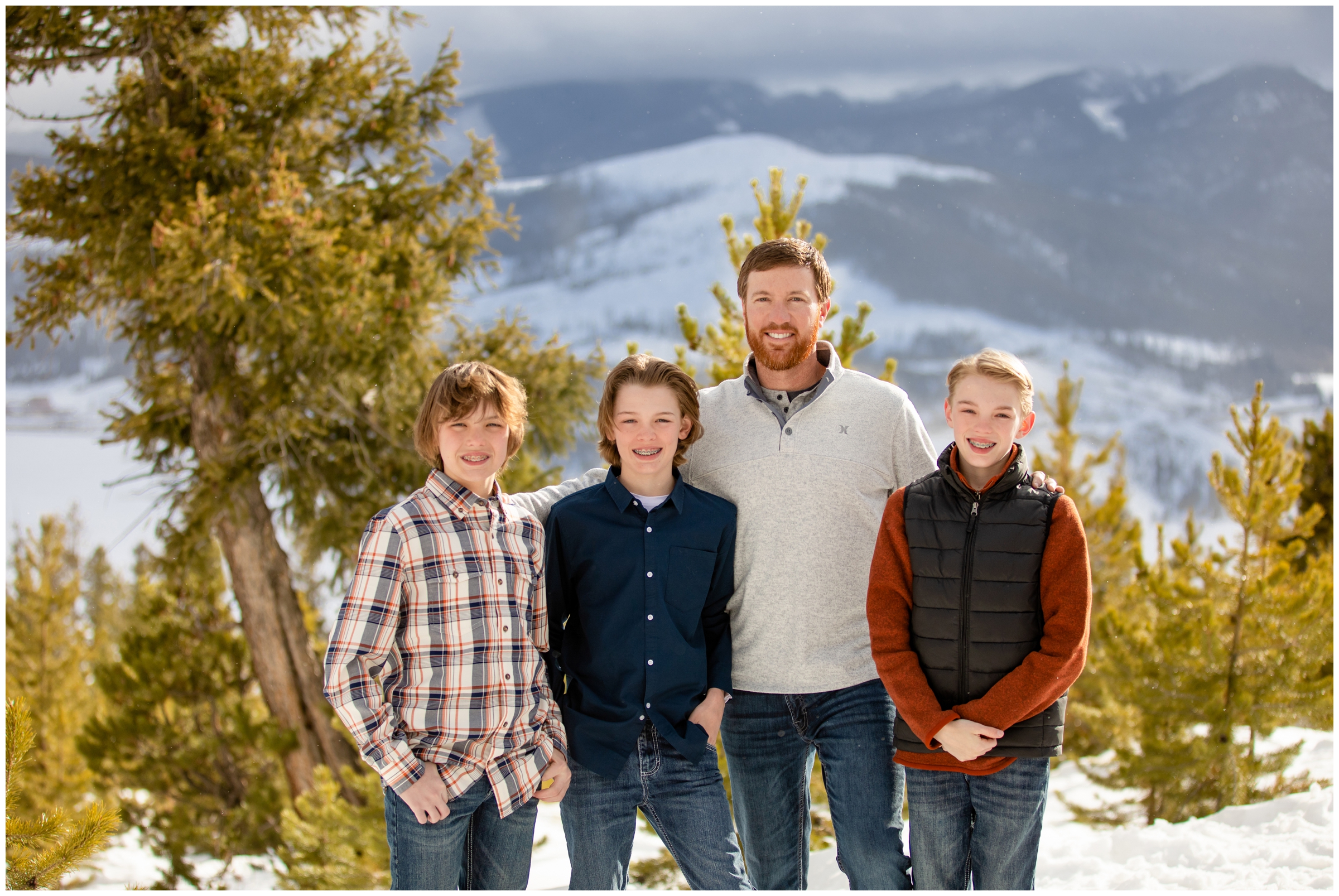 dad with sons posing in the snow with mountains in background at Sapphire Point in Dillon CO