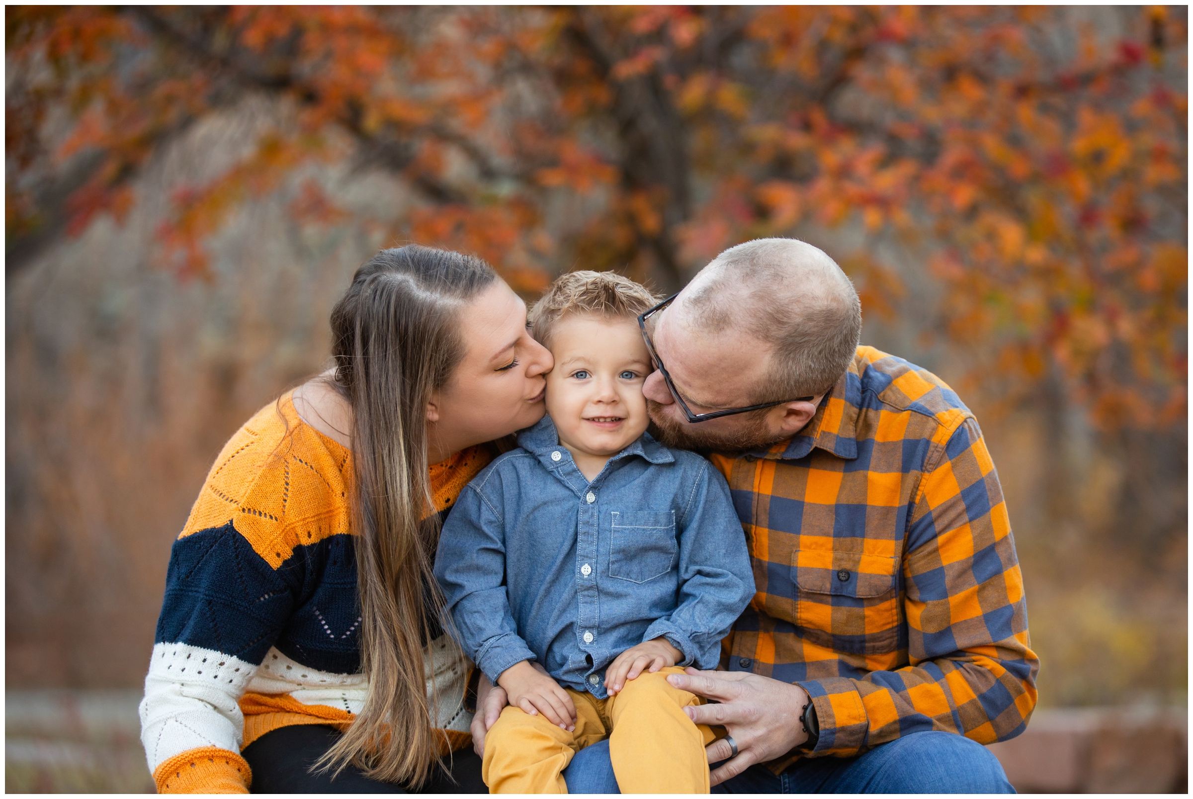 parents kissing son on cheeks during colorful fall family photos in Lyons CO 