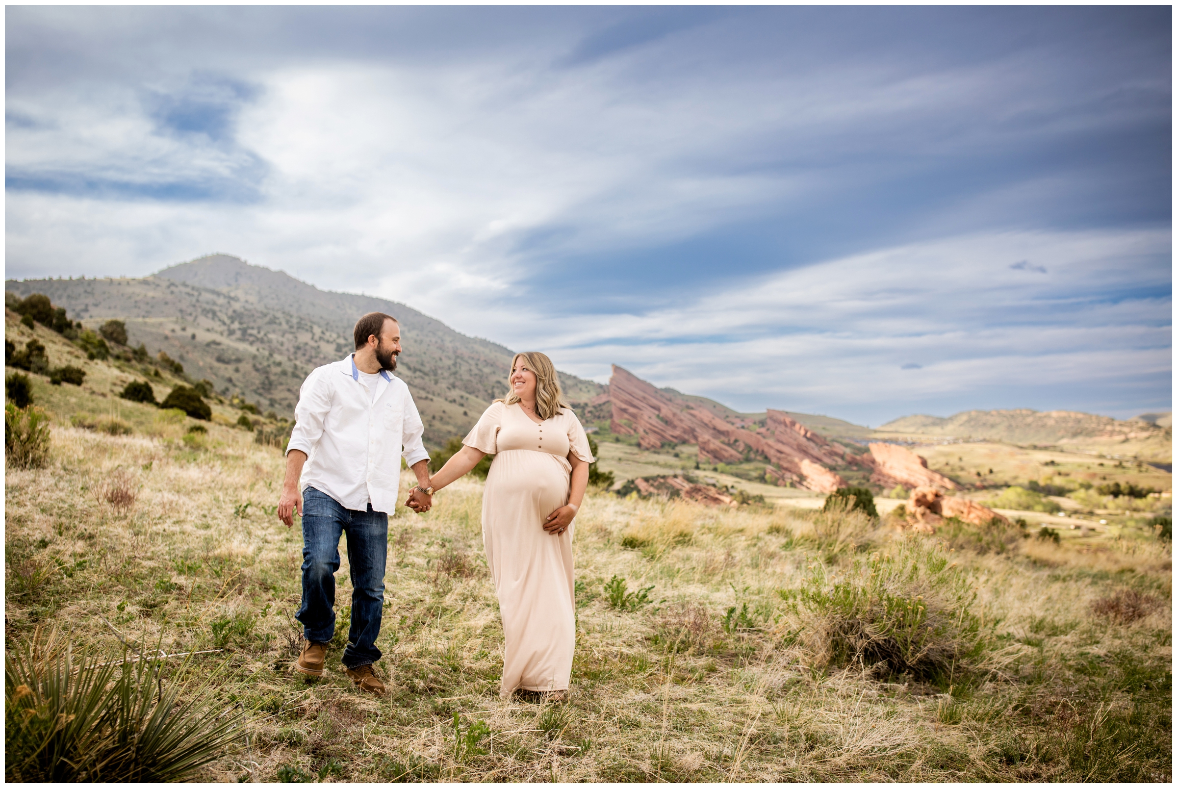 couple walking with red rocks in background during maternity pictures in Morrison Colorado 