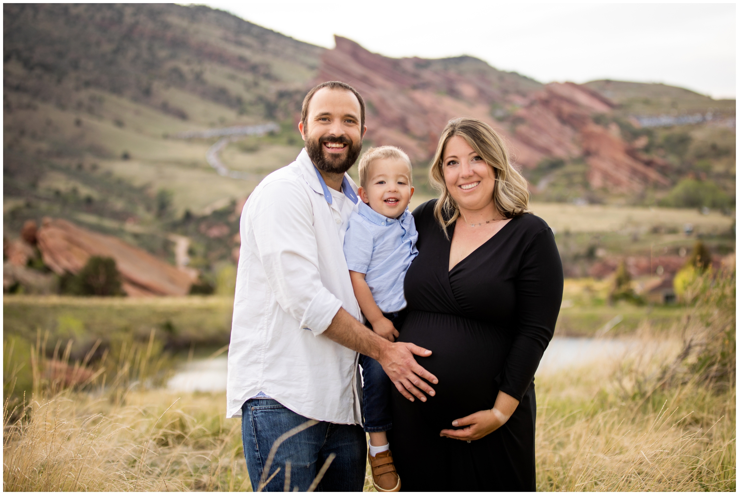 family posing with red rocks in background during Colorado family maternity photos at Mount Falcon by Denver portrait photographer Plum Pretty Photos
