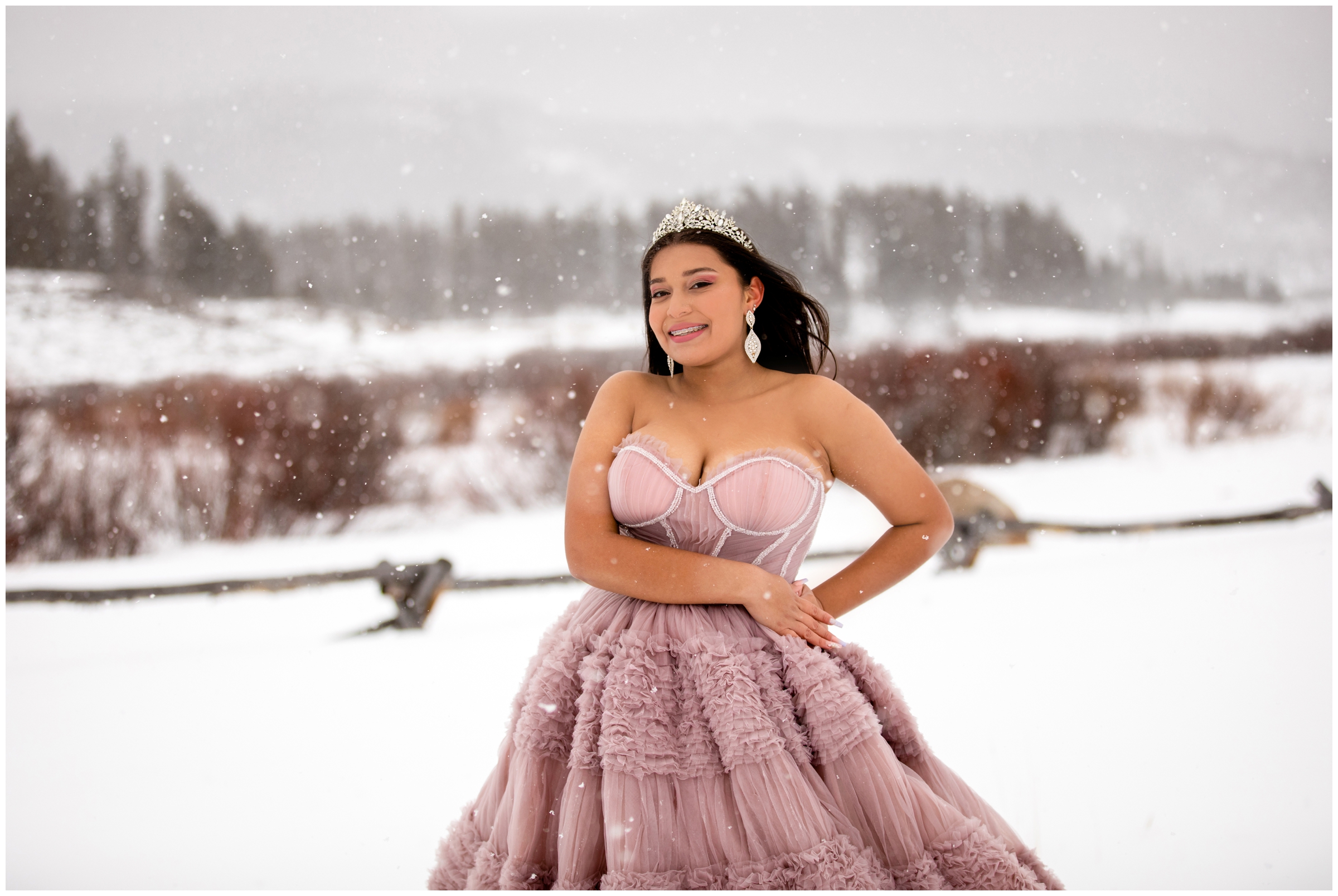 teen girl posing in pink prom dress during snowy winter portrait session in Winter Park Colorado