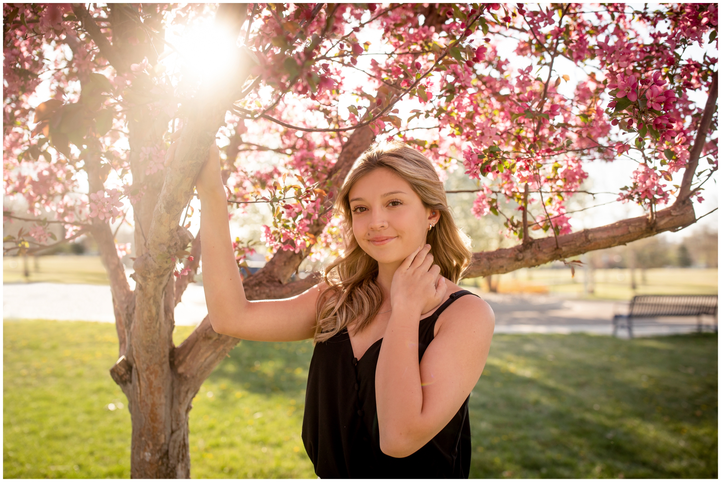 teen girl posing with pink cherry blossom tree during spring Colorado senior pictures in Longmont 