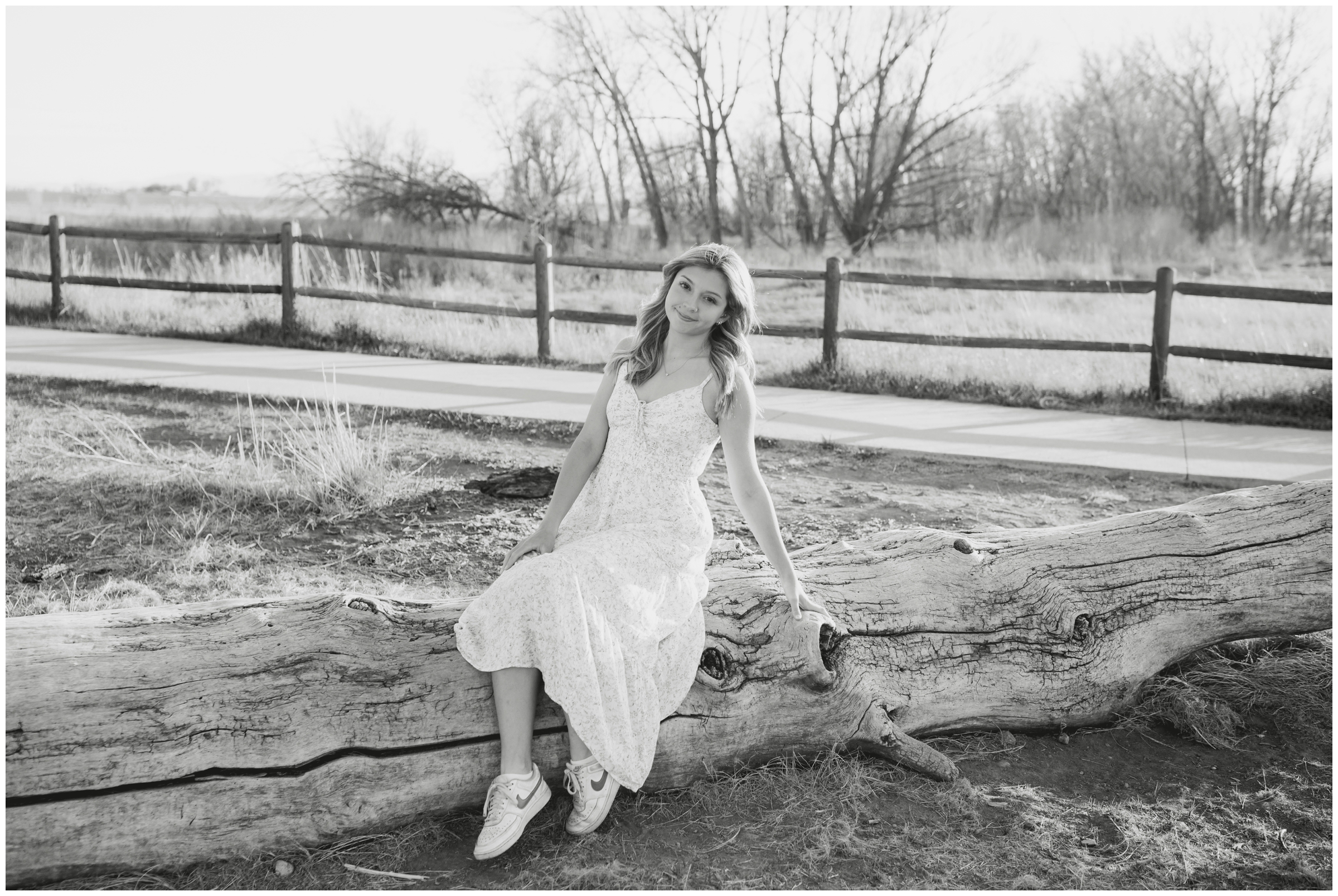 teen sitting on tree log during Skyline High School Longmont graduation photo shoot