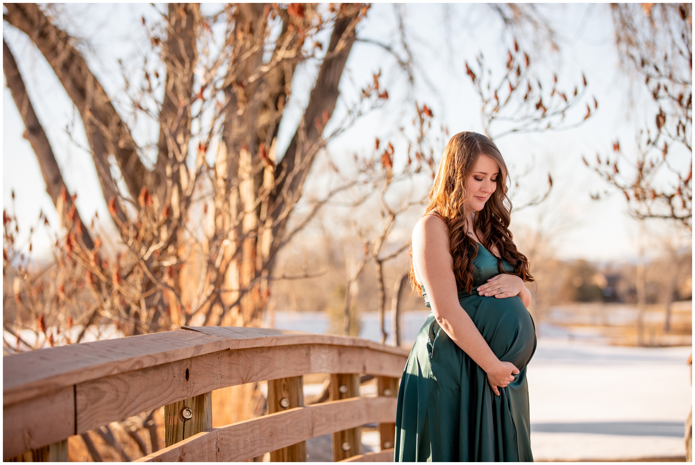 pregnant woman in emerald green dress posing on wooden bridge at Hudson Gardens during maternity photo shoot