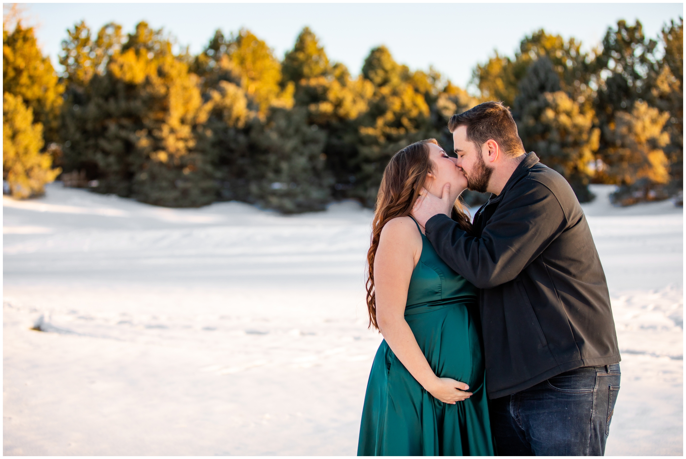 couple kissing in the snow during Colorado winter maternity pictures at Hudson Gardens
