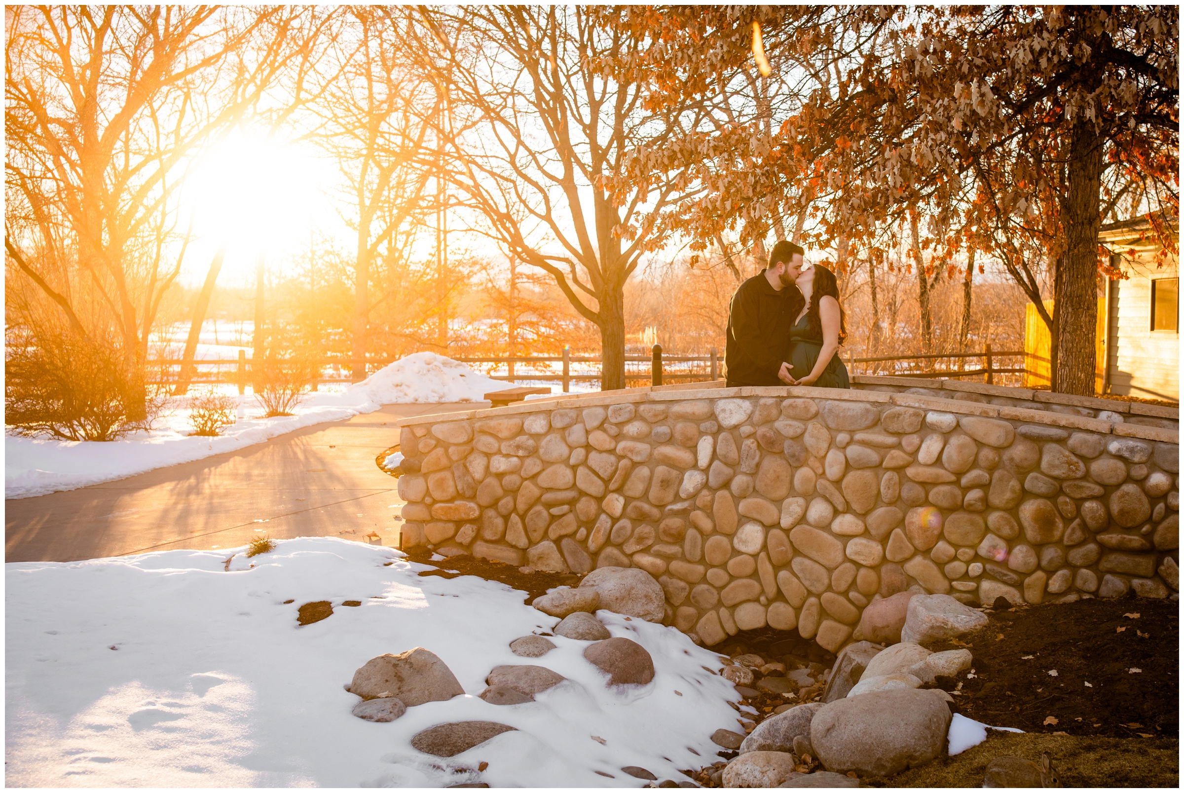 couple kissing on a bridge at Hudson Gardens during winter maternity photos in Denver