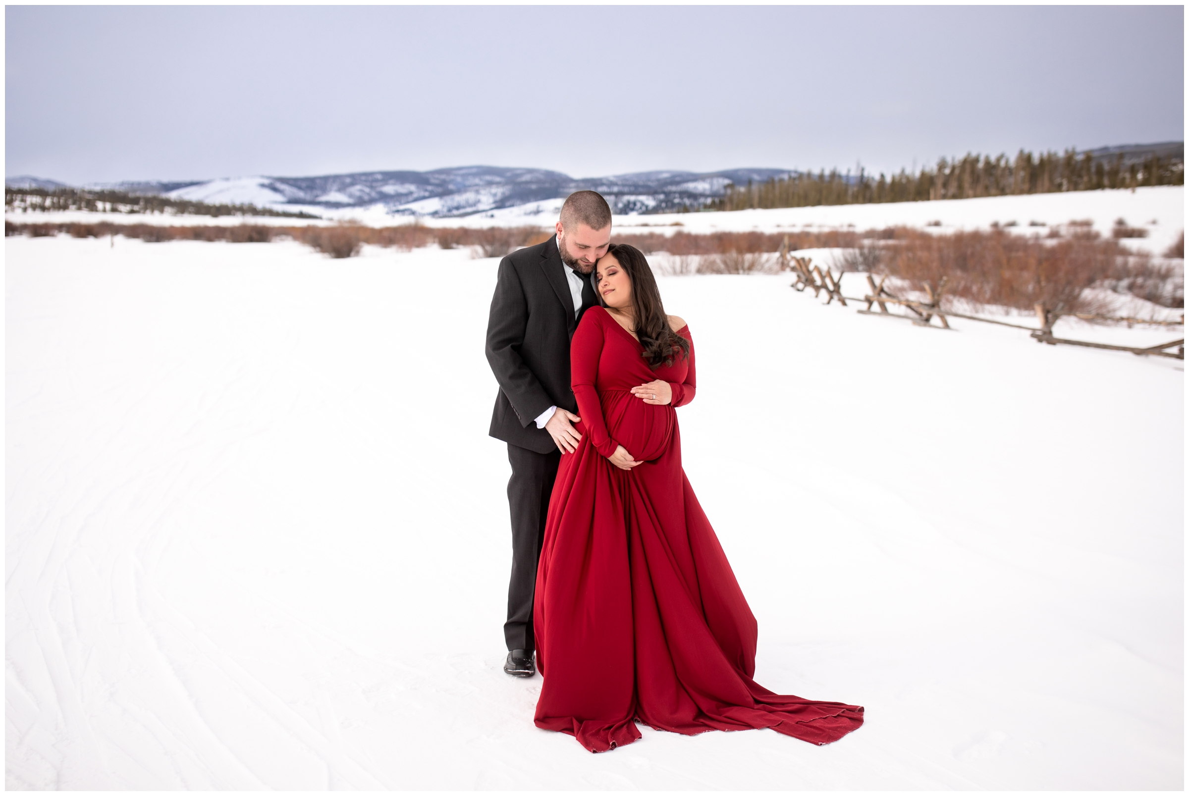 couple cuddling in the snow during Winter Park Colorado maternity portraits at Devils Thumb Ranch