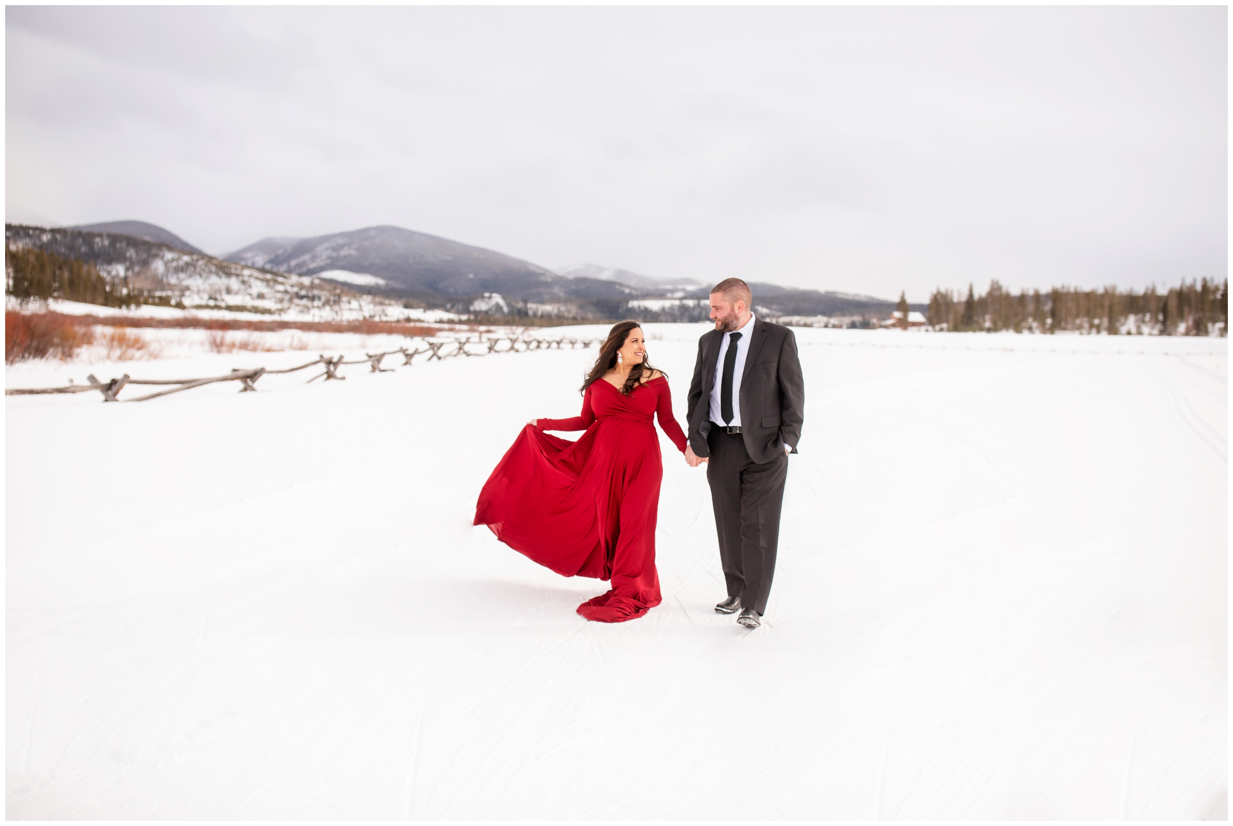 couple holding hands and walking in the snow during Winter Park Colorado maternity photos