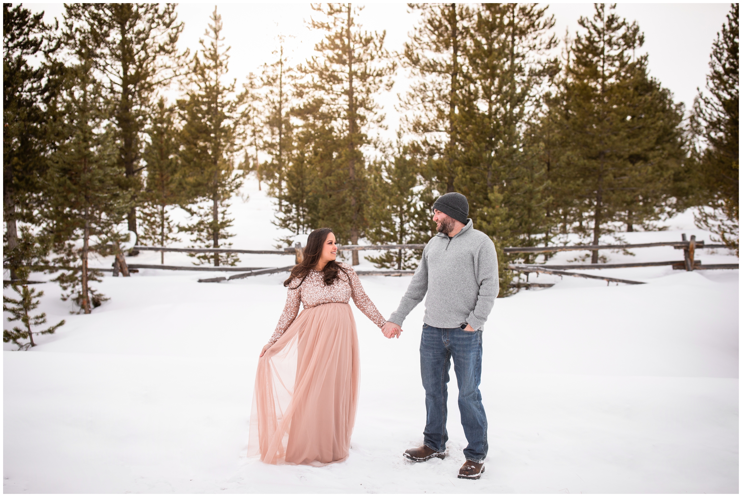 couple holding hands in the snow during Winter Park Colorado maternity pictures 