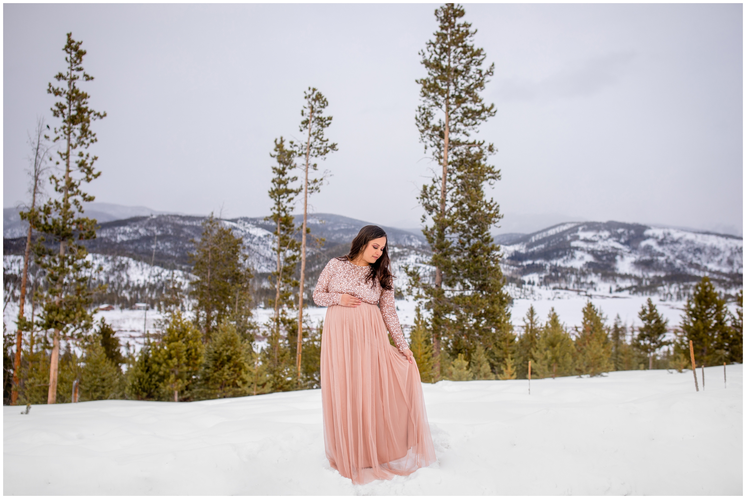 pregnant woman in sparkly pink dress posing for Colorado winter maternity portraits at Devil's Thumb Ranch by Winter Park photographer Plum Pretty Photography