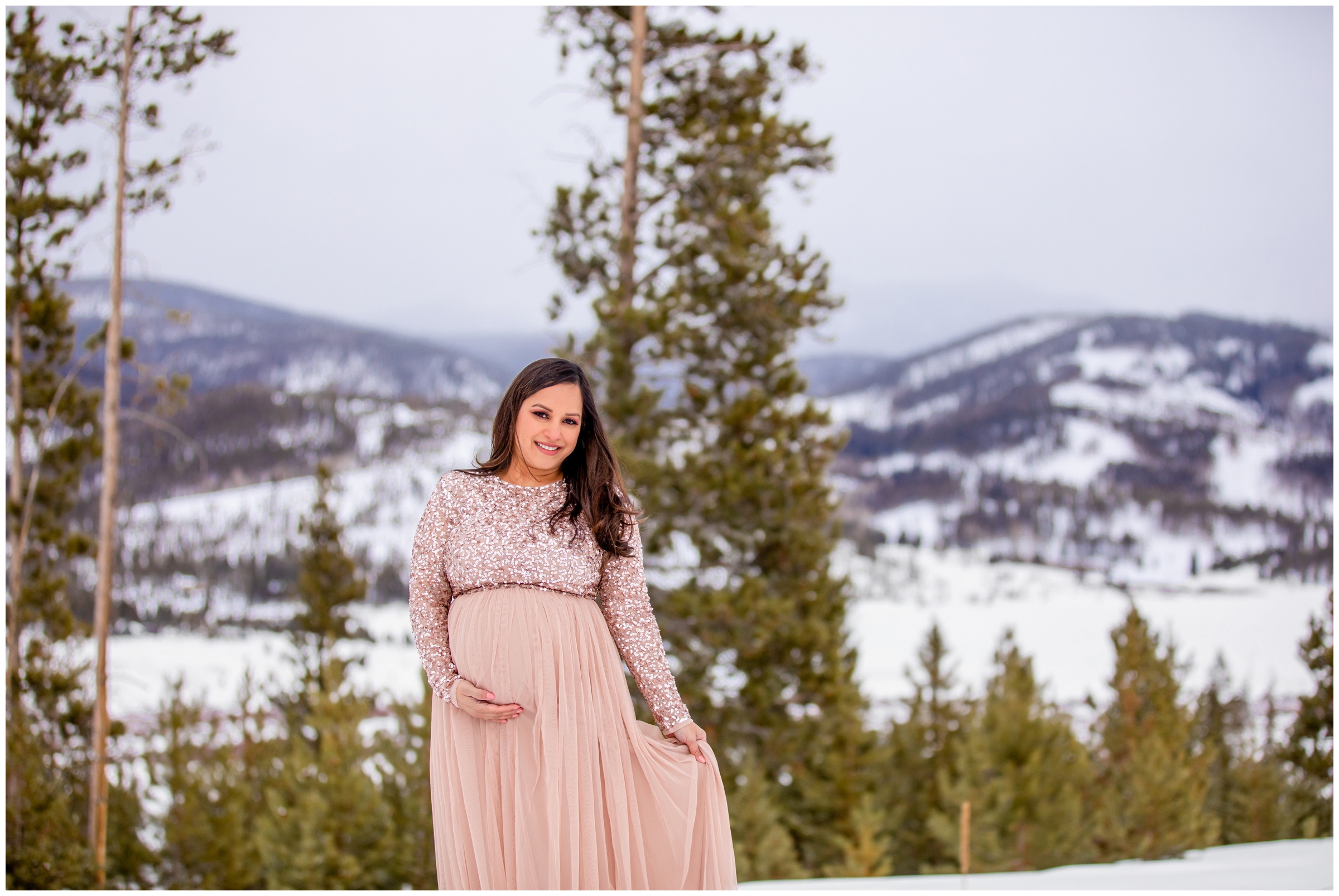 woman in sparkly pink dress in the snow during mountain maternity session in Winter Park