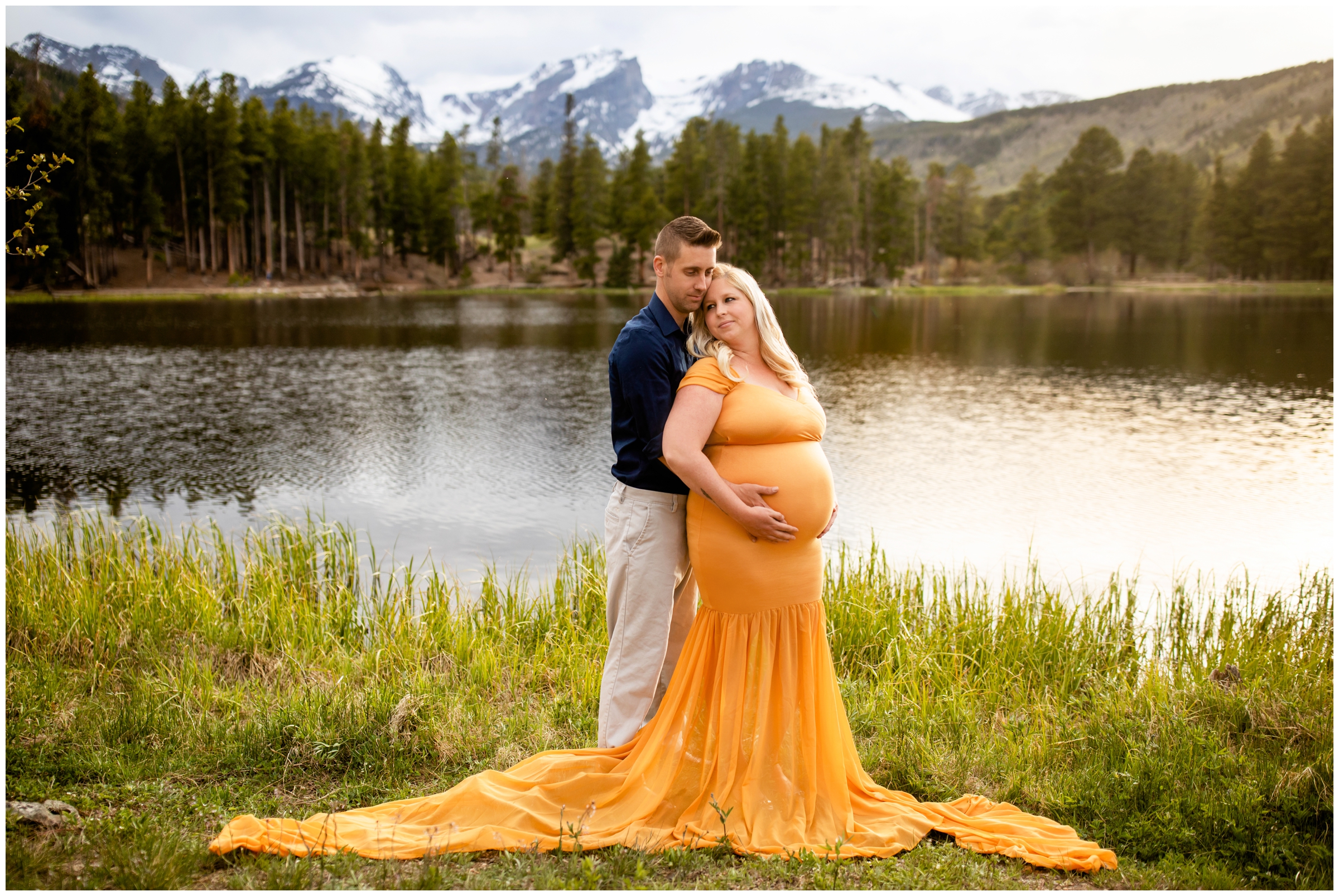 couple cuddling next to a mountain lake during Estes Park maternity photography session in RMNP