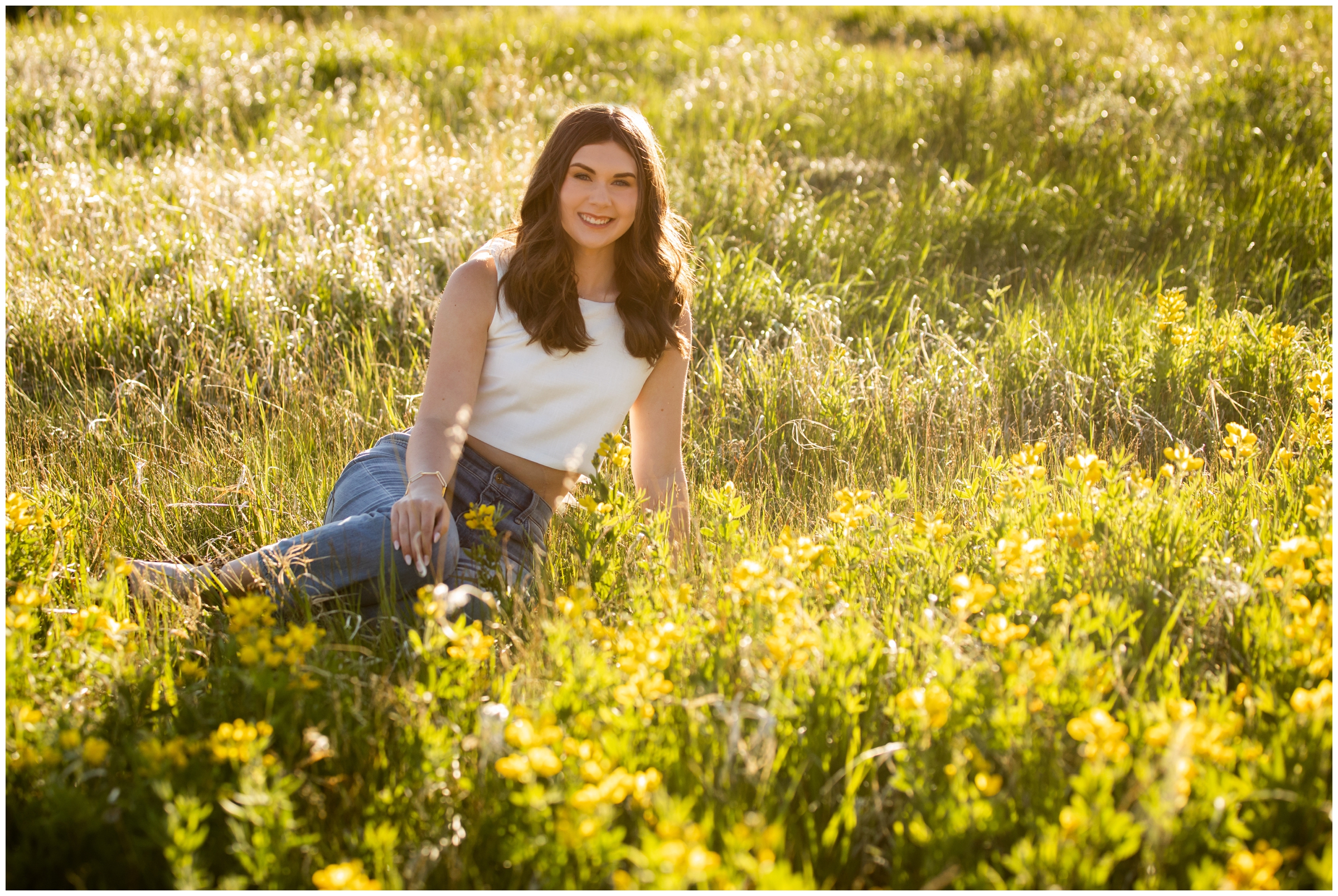teen sitting in field of wildflowers during summer senior photos in Estes Park Colorado